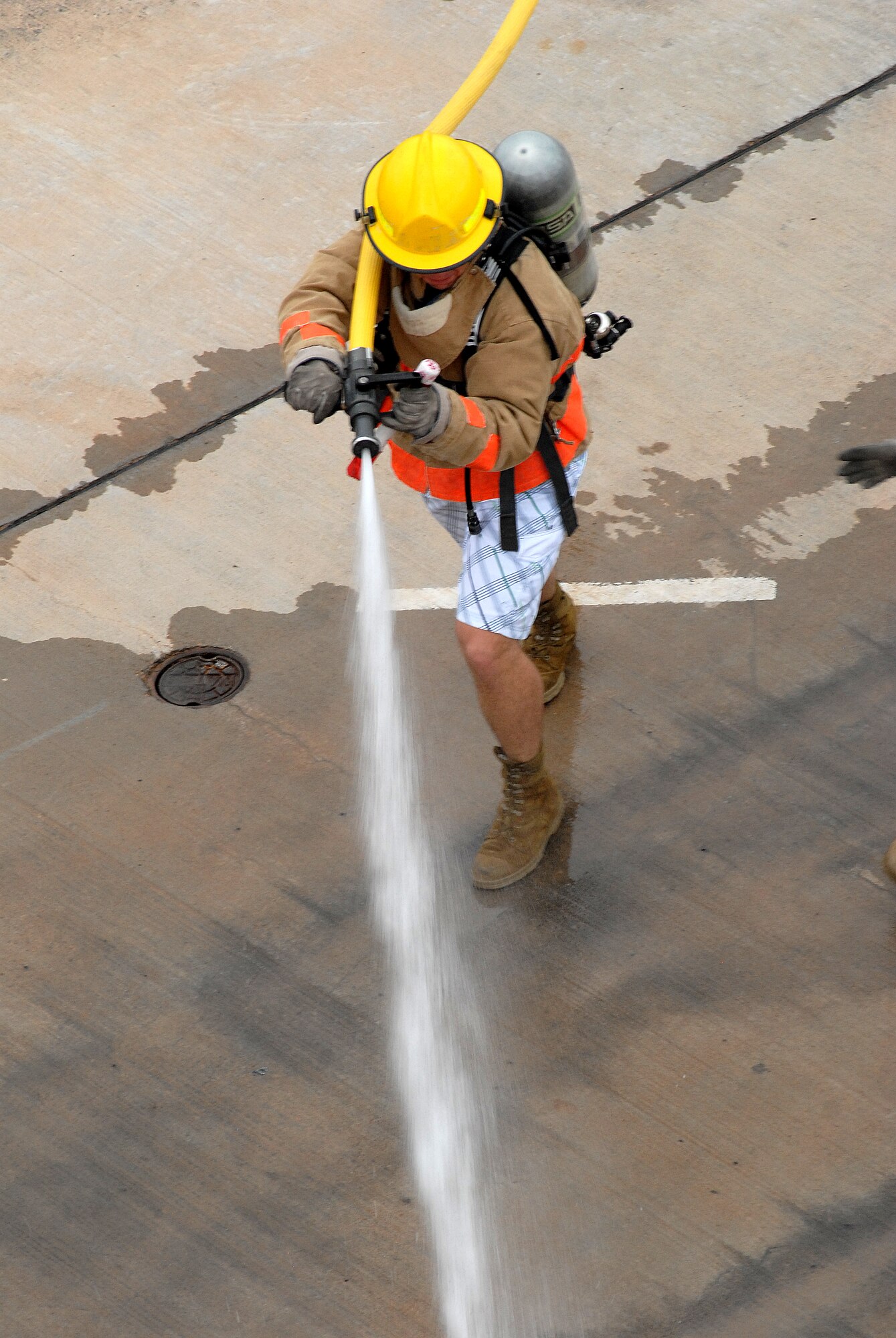 A competitor drags a hose 75 feet to a predetermined location in order to knock down a target with a stream of water during the 2nd quarter Goodfellow AFB Rookie Firefighter Challenge June 12.  This is just one leg of a relay that is call the toughest two minutes in sports which pushes teams and individuals to their physical limits. (U.S. Air Force photo/Master Sgt Randy Mallard)