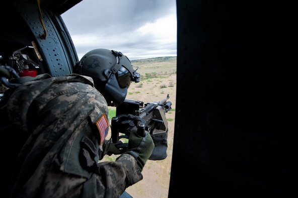 Army Staff Sgt. Marc Belo, UH-60 Black Hawk crew chief of 2nd Battalion, 135th Aviation Regiment, Colorado Army National Guard Army Aviation Support Facility, Buckley Air Force Base, scans the terrain on decent to a landing zone during a live fire demonstration at Fort Carson, Colo. June 12, 2010. (U.S. Air Force photo/Master Sgt. John Nimmo, Sr.) (RELEASED)