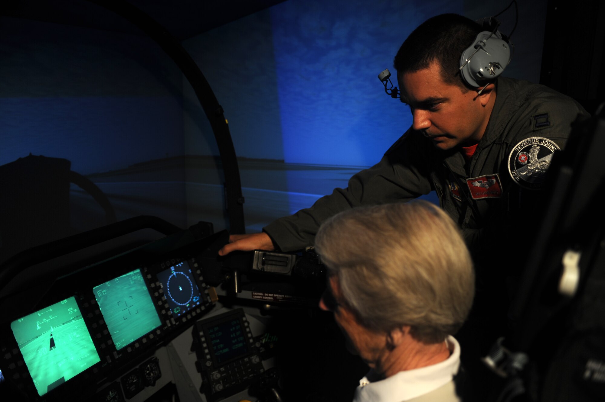SEYMOUR JOHNSON AIR FORCE BASE, N.C. -- Capt. Nathan White assists Kris Frankfurt in a flight simulator during the Air Force Civic Leader Alumni Group base tour here June 11, 2010. The machine simulates what it would be like to fly an F-15E Strike Eagle and is used as initial training for Basic Course students and refresher training for seasoned pilots and weapons system officers. Captain White is a WSO with the 333rd Fighter Squadron. Mrs. Frankfurt is the wife of Bill Frankfurt, a civic leader from Oklahoma City. (U.S. Air Force photo/Staff Sgt. Heather Stanton)