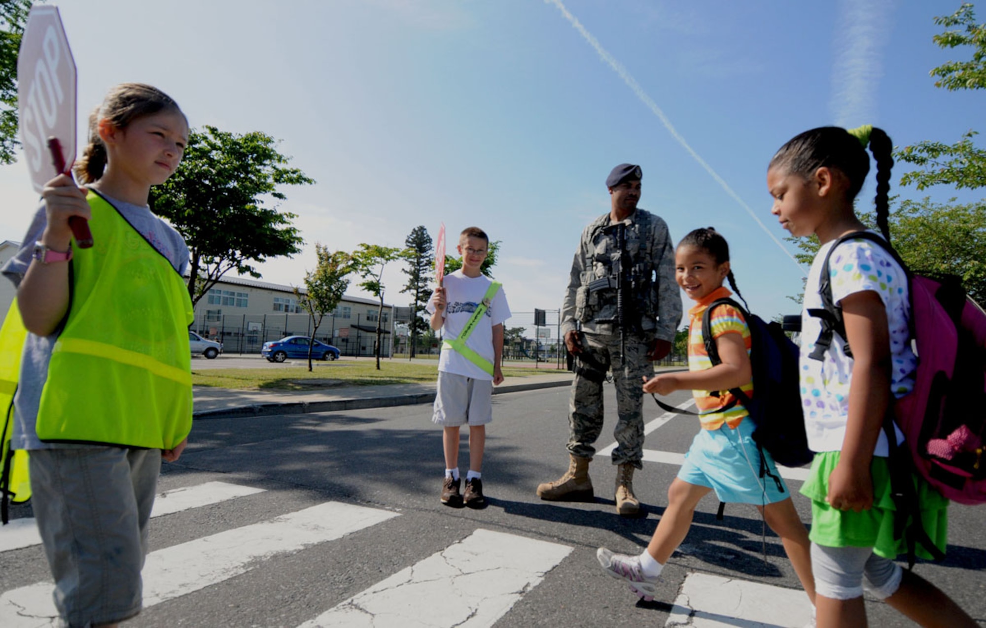 MISAWA AIR BASE, Japan -- Gabriella Kerwin, daughter of Tech. Sgt. Matthew Jones, and Tyler Dallies, son of Staff Sgt. Ken Dallies, direct pedestrian traffic alongside Airman 1st Class Steven Howard, 35th Security Forces  Squadron patrolman, June 15, at a high-traffic cross walk near Sollars Elementary School. Nearly 100 students from Sollars and Cumming Elementary school help the 35th SFS keep the base safe by volunteering as crossing guards in their school’s safety patrol program. (U.S. Air Force photo/Senior Airman Jessica Lockoski)  