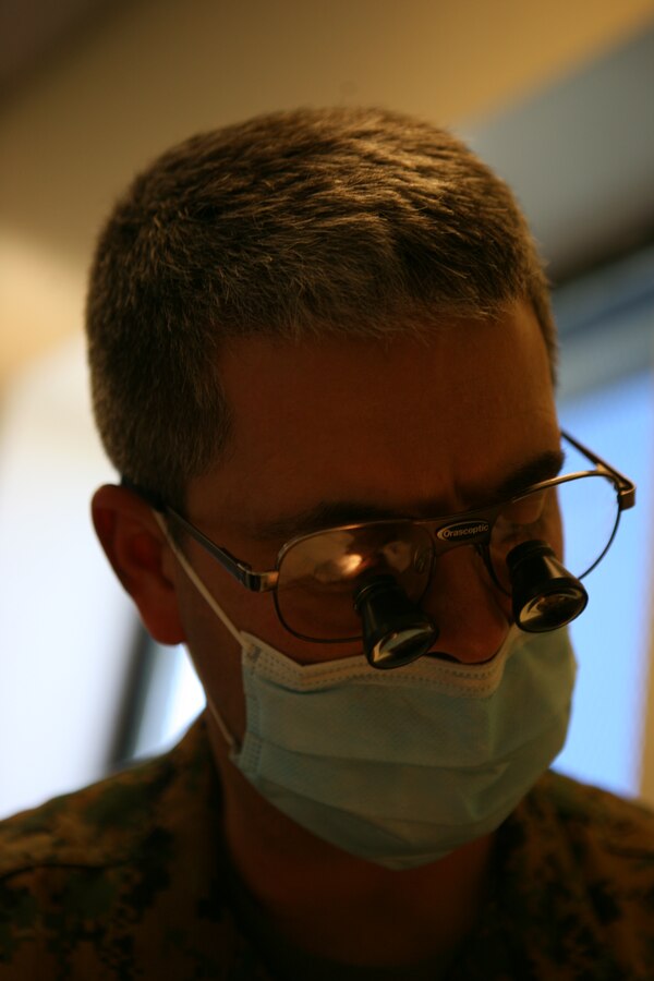 Cmdr. Thomas Olivero, a dental officer with 4th Marine Logistics Group, examines a patient's mouth.