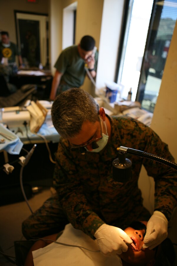 Cmdr. Thomas Olivero, a dental officer with 4th Marine Logstics Group, fills a cavity for Pfc. Brandon Johnson, an infantryman with Company K, 3rd Battalion, 23rd Marine Regiment.