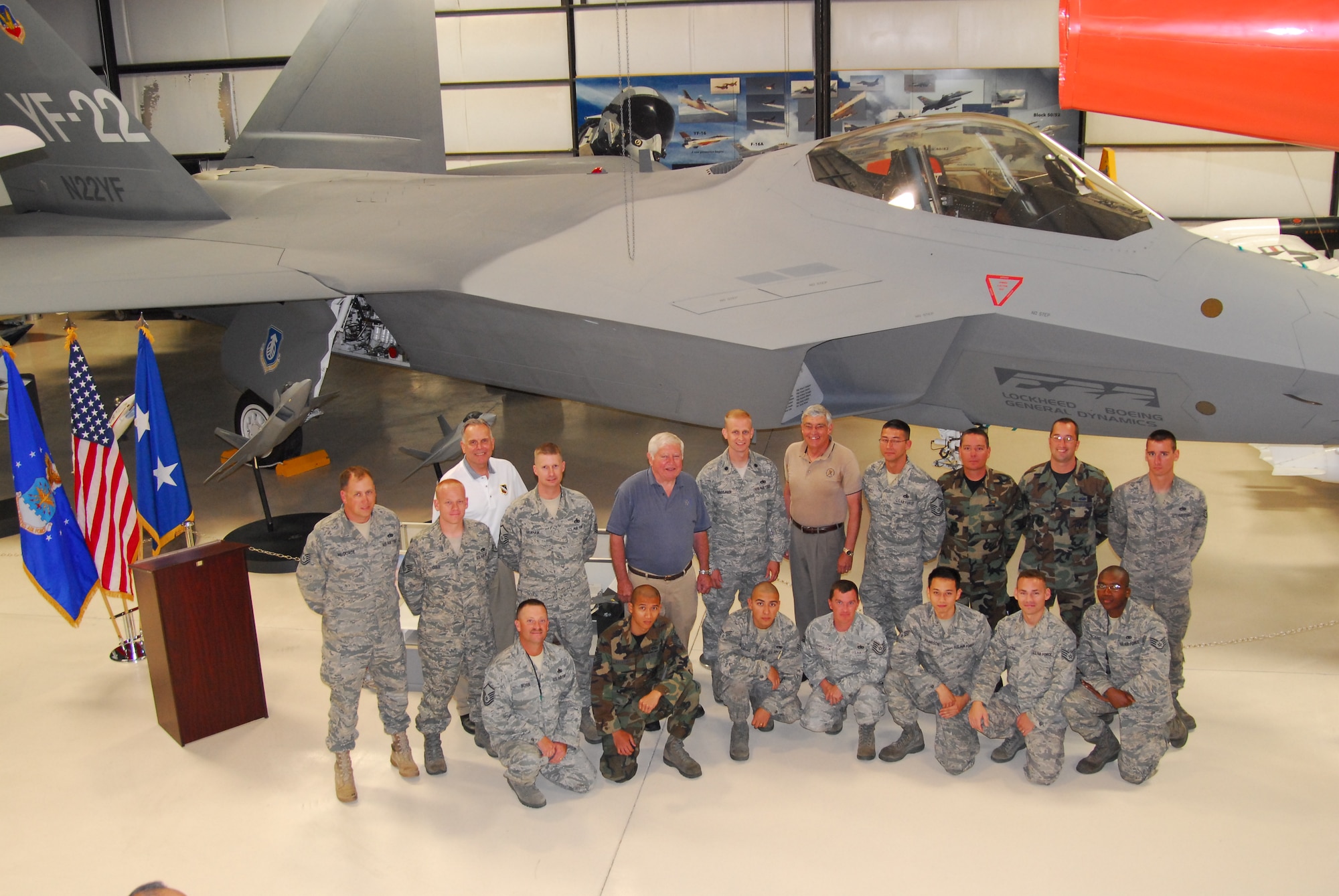 Fourteen of the 22 Airman who were hands-on in the process of bringing the first YF-22 Raptor prototype built, pose in front of the aircraft with Mr. David Ferguson (blue shirt), first Raptor test pilot, Mr. Tom Morgenfeld (tan shirt), last Raptor test pilot and Mr. Fredrick Johnsen (white shirt), Air Force Flight Test Center Museum director, that were instrumental in bringing back to Edwards, its flight-test home.