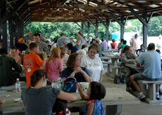 Airmen and family members take shelter from the scorching heat to enjoy free, freshly prepared barbeque cooked by base volunteers at the annual base picnic June 11, 2010 on Joint Base Charleston, S.C. Activities and entertainment were not only accessible at the picnic grounds, but also spanned to the base pool and theater offering free swimming and a special family matinee at a discount price. (U.S. Air Force photo/ Senior Airman Timothy Taylor)