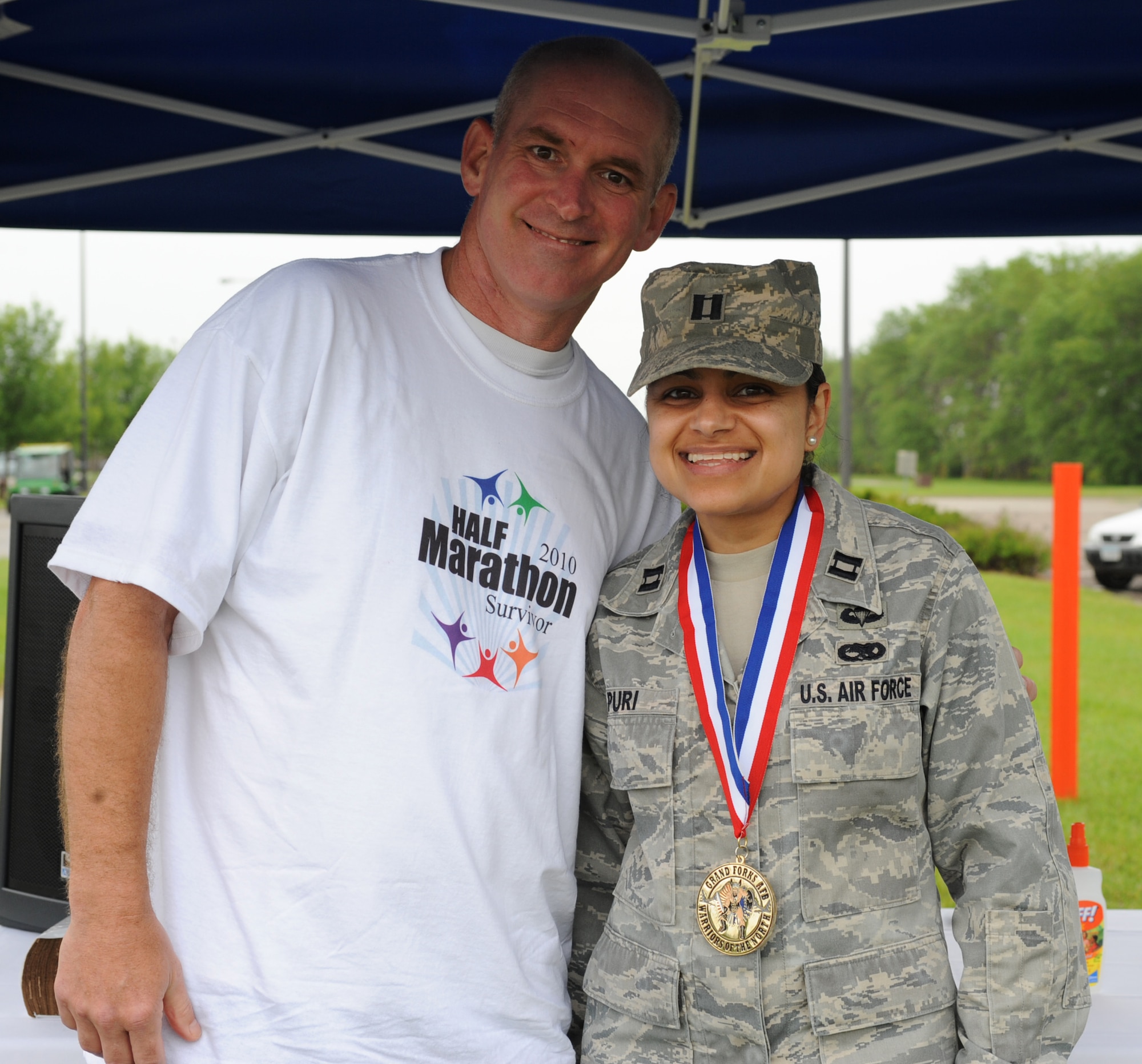 Col. John Quinn, 319th Air Refueling Wing vice-commander and Capt. Aarti Puri, 319 ARW wing executive officer (from left to right), pose for a picture after Colonel Quinn awarded Captain Puri the first place medal in the female category for the Grand Forks Air Force Base Half-Marathon, June 15. Captain Puri completed the half-marathon in one hour, 42 minutes and 25 seconds. (U.S. Air Force photo by Airman 1st Class Amber Price)  