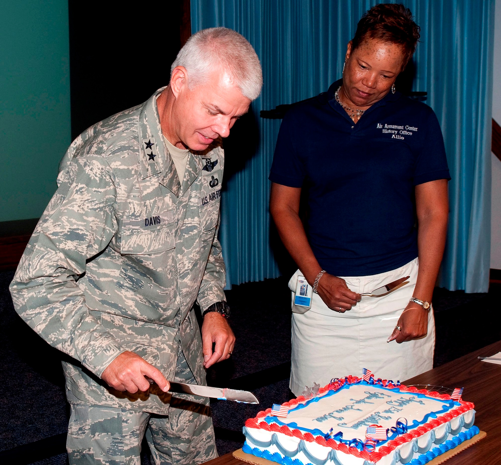In celebration of the official 75th birthday of Eglin Air Force Base, Maj. Gen. C.R. Davis, Air Armament Center commander, cuts the first piece of cake at his senior staff meeting June 15. Alice Malcolm, right, and other staff members of Eglin's History office presented the cake to the commander. The Army Air Corps activated the Valparaiso Bombing and Gunnery Range on June14, 1935, with a detachment of 15 enlisted men commanded by then Lt. Arnold H. Rich. (U.S. Air Force photo/Bruce Hoffman)