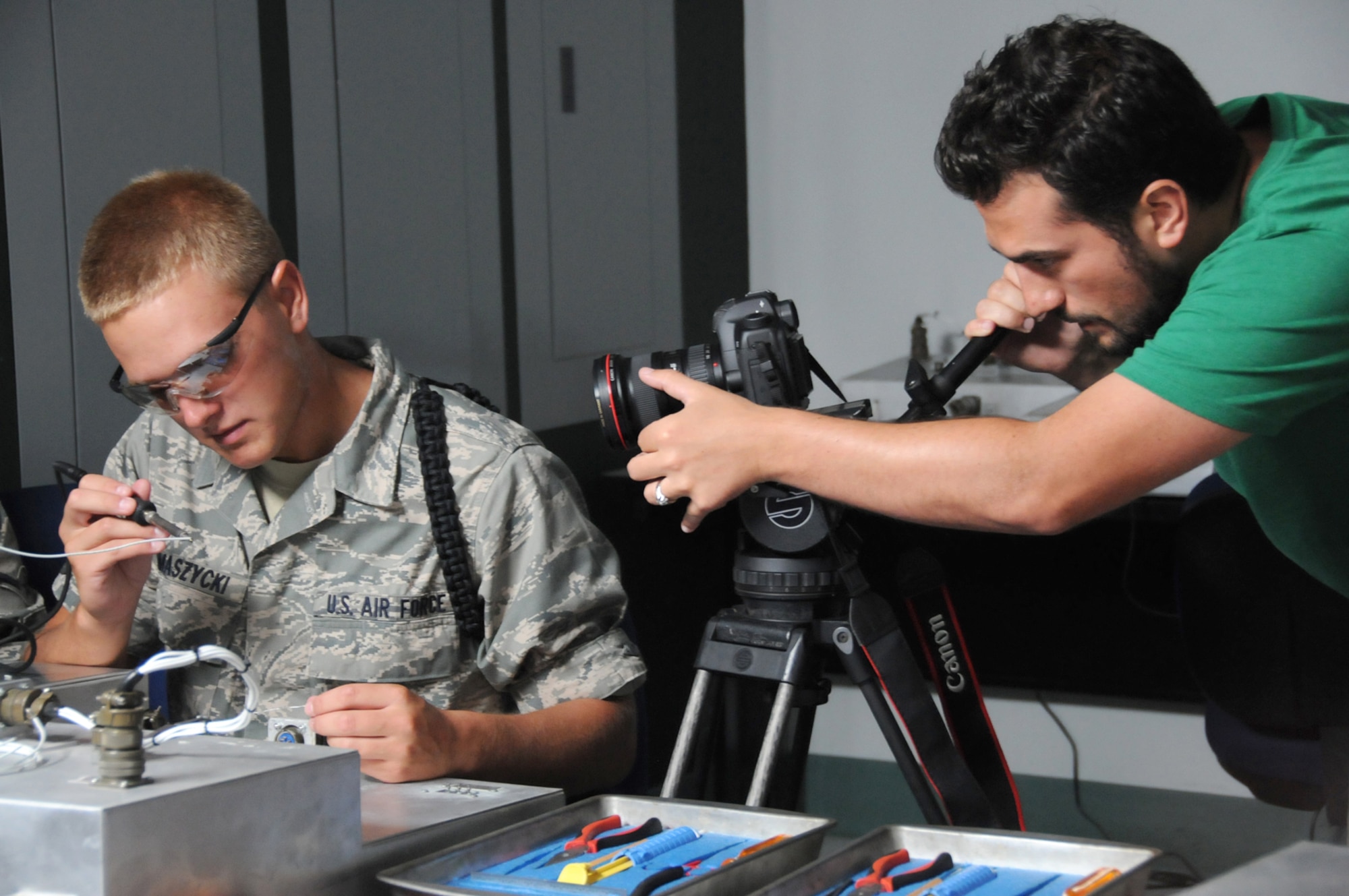 Airman Basic Alan Tomaszycki, a electronic principles student in the 332nd Training Squadron, solders a wire to a terminal post connection as videographer Julio Quintana moves in for a closeup shot June 10 in Dolan Hall during a commercial shoot by GSD&M from Austin, Texas.  The video team spent four days at Keesler last week to film footage for the Air Force Recruiting Service.  The final product will include footage from Keesler and other training bases to refresh portions of the recruiting service’s national Web site at airforce.com.  (U.S. Air Force photo by Kemberly Groue)
