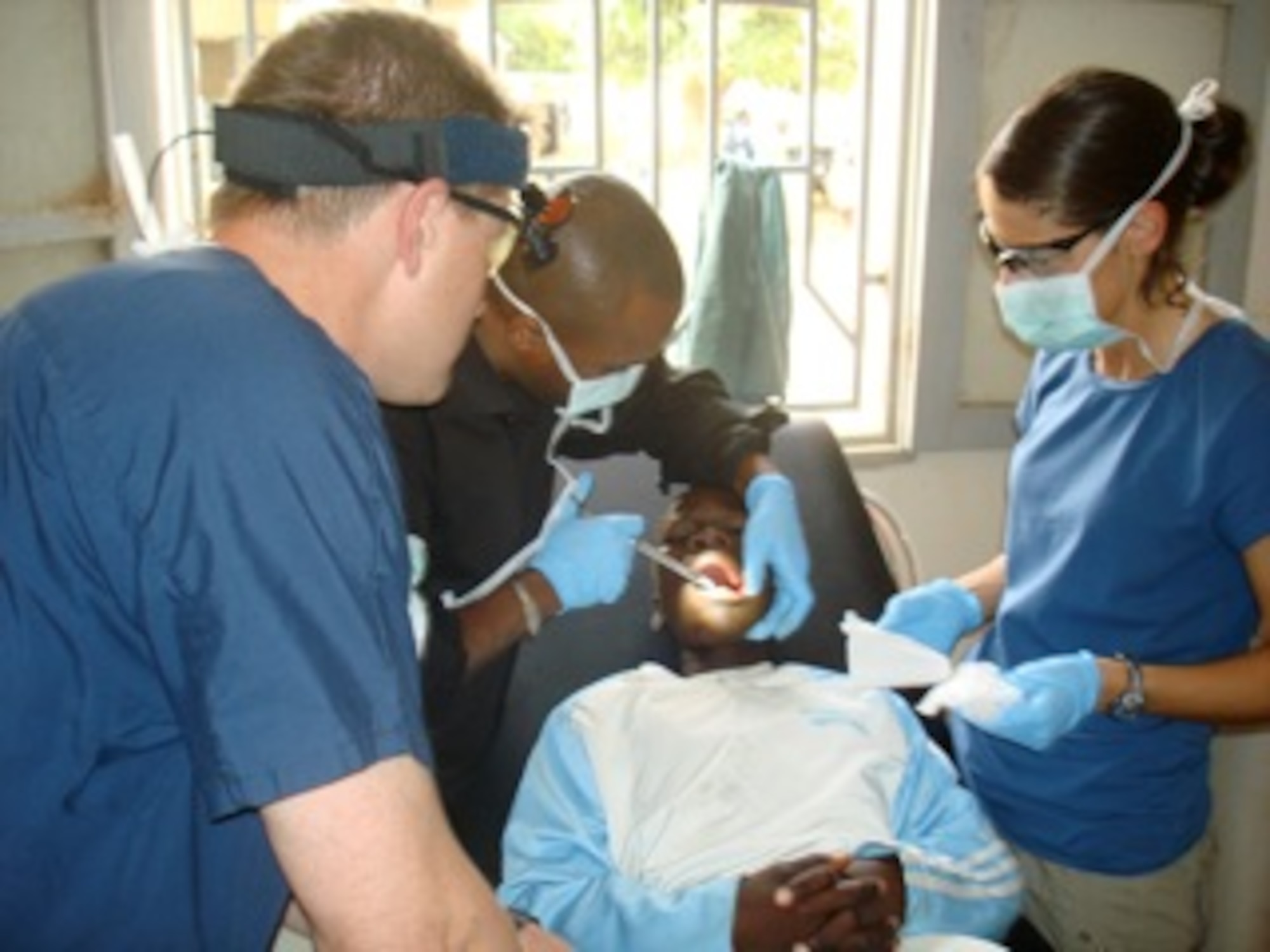 Captain Tad Tholstrom (far left) and Staff Sgt. Leah Potter (far right), 1st Special Operations Medical Group dentist and dental technician, operate alongside a local dentist while treating a patient in West Africa.  The Hurlburt Airmen were temporarily assigned to the West Africa region in support of Exercise Flintlock, an annual exercise  that focuses on improving interoperability between the militaries of the United States, Europe and Northern and Western African countries.(courtesy photo)