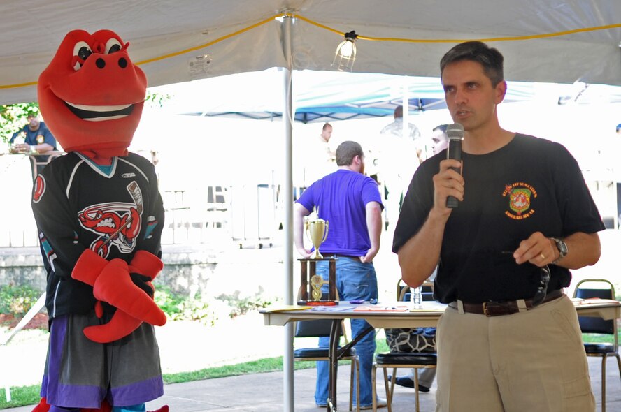 BARKSDALE AIR FORCE BASE, La. – Col. Steven Basham, 2d Bomb Wing commander, give opening remarks during the Barksdale Crawfish Festival June 11 as Clawed, the official mascot of the Mudbugs of Bossier-Shreveport Hockey Team, stands by. (U.S. Air Force photo by Senior Airman Alexandra M. Boutte) (RELEASED)