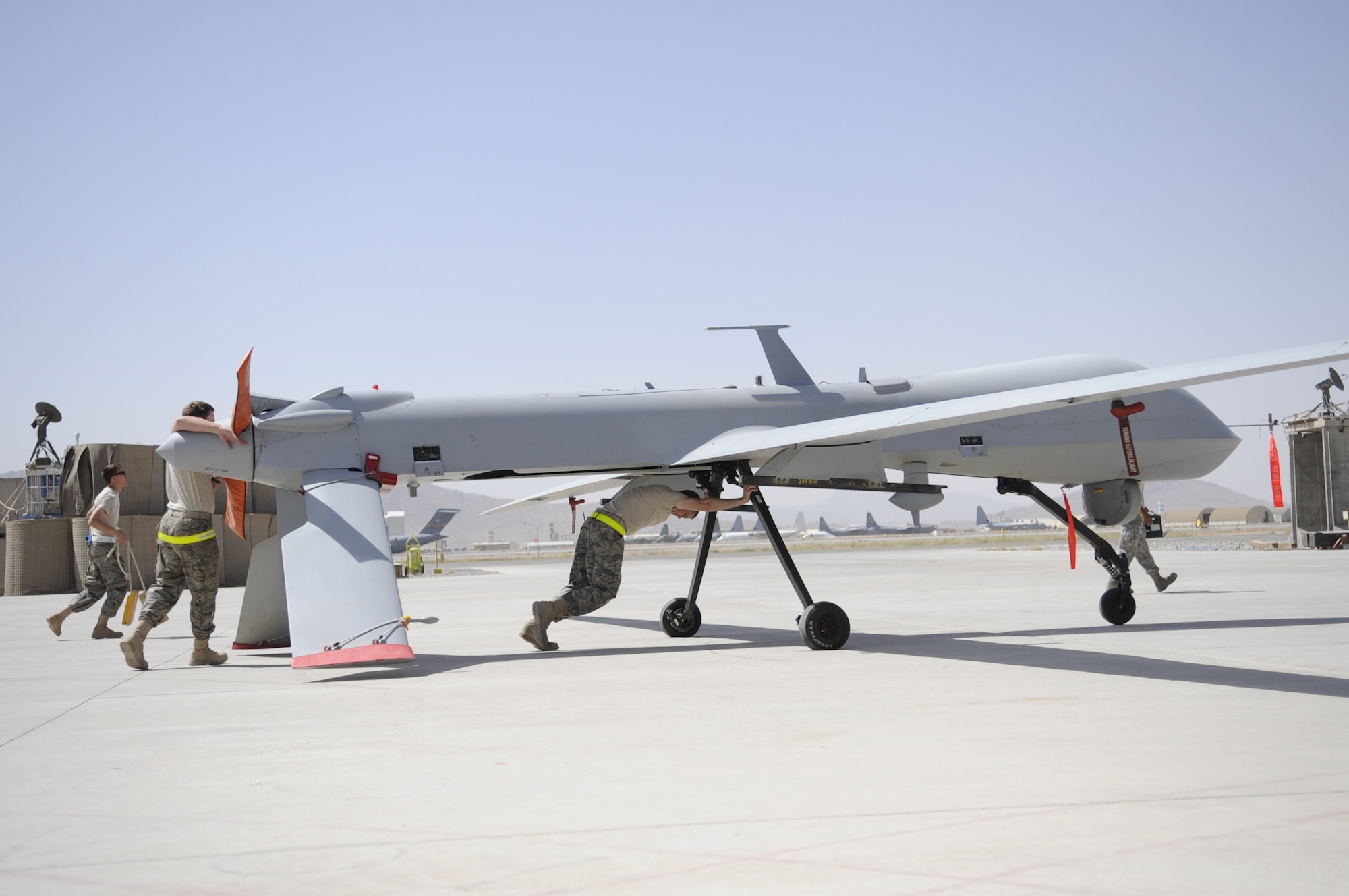 Members of the 451st Expeditionary Aircraft Maintenance Squadron unit push an MQ-1 Predator toward a hangar for a routine maintenance inspection shortly after landing. The remotely piloted aircraft are launched, recovered and landed by members of the 62nd Expeditionary Reconnaissance Squadron. The reconnaissance unit  is comprised of deployed Air Force members from the 432nd Operations Group, Creech Air Force Base, Nev., and the 27th Special Operations Group, Cannon AFB, N.M. Additionally, the British Royal Air Force also operates RPAs from Creech AFB and they too are deployed to KAF. (U.S Air Force photo by Senior Airman Nancy Hooks)
