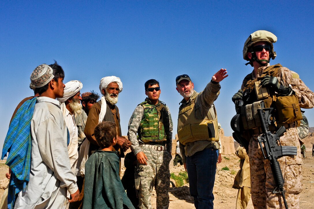 Darren Richardson, U.S. Agriculture Department employee, points to a nearby canal with U.S. Marine Corps Maj. Jeffrey Seavy and members from a local Kuchi tribe residing in the Bawka district in Farah province, Afghanistan, June 12, 2010. Seavy, the 1st Marine Expeditionary forward liaison officer to Provincial Reconstruction Team Farah, visited three villages in the district to gather information on the needs of the village residents.