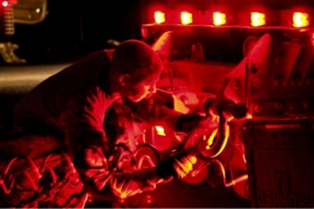 U.S. Army Sgt. Tyler Clausing hooks up a trailer to a Palletized Load System truck after dark on Camp Khalid, Iraq, June 11, 2010. Clausing is assigned to the 82nd Airborne Division's Company E, 1st Battalion, 504th Parachute Infantry Regiment, 1st Advise and Assist Brigade.