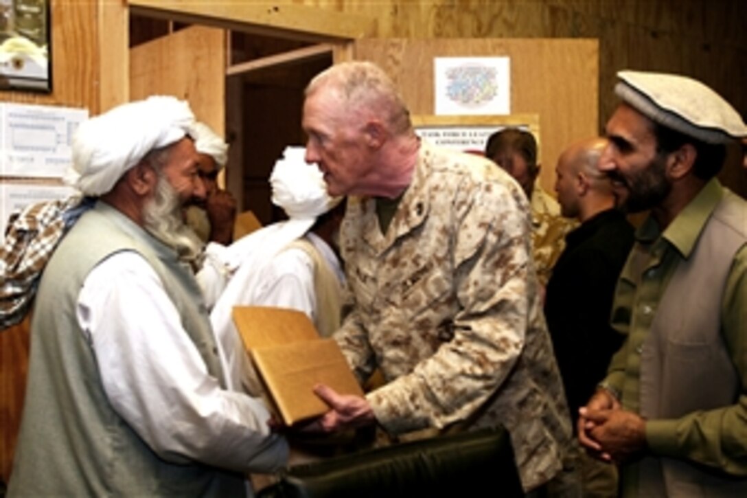 U.S. Marine Corps Maj. Gen. Richard P. Mills, center, the commanding general of I Marine Expeditionary Force Forward, presents Mullah Muhammed Ismail Naqibi, a Musa Qal’eh district religious leader, with a token of appreciation after hosting a meeting with local religious leaders, known as mullahs, on Camp Leatherneck, Afghanistan, June 13, 2010. 