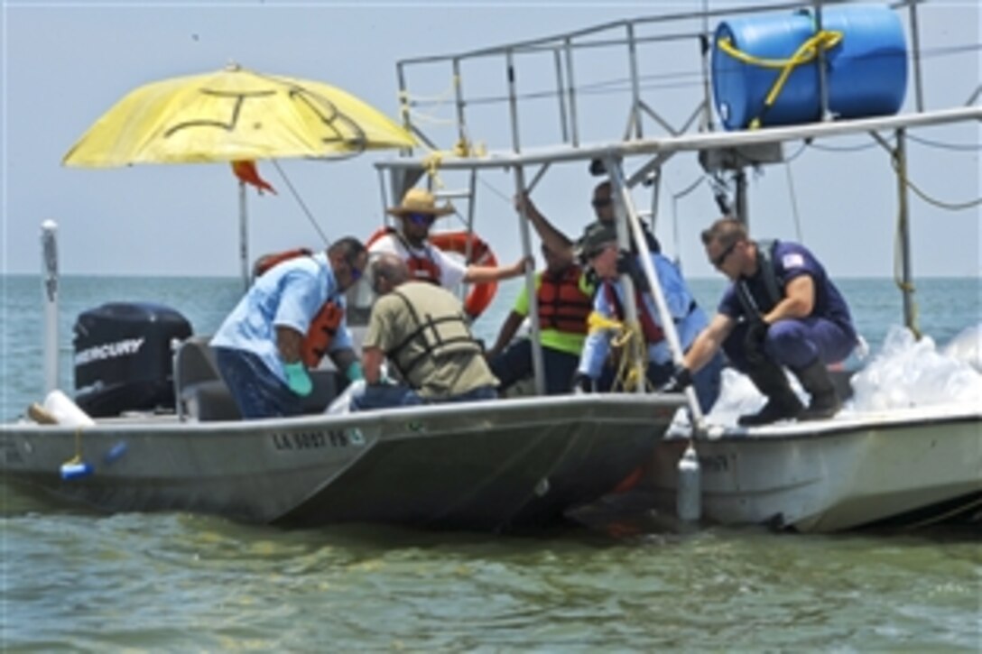 U.S. Coast Guard Petty Officer 3rd Class Christopher Wright works with local and commercial fisherman contracted by BP to discard old boom in Port Fourchon, La., June 15, 2010. The crews will replace the old boom with a new, absorbent boom as a preventative measure to protect the marshes in Timbalier Bay, La. 