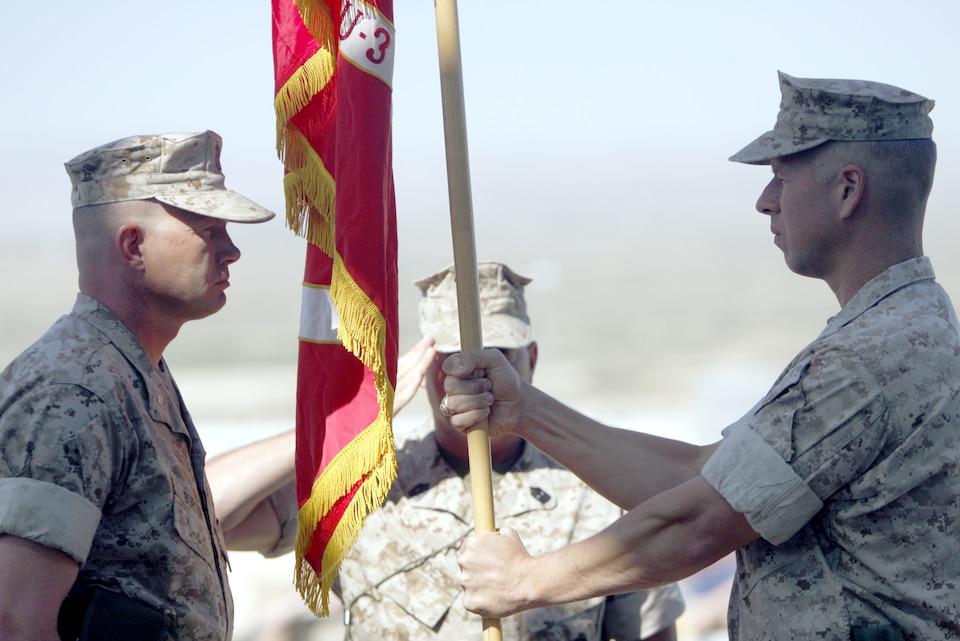 Lt. Col. James W. Frey [right], the outgoing commander, hands Marine Unmanned Aerial Vehicle Squadron 3's unit guidon to Lt. Col. Timothy G. Burton [left], the incoming commander, June 17 at the Combat Center's Lance Cpl. Torrey L. Gray Field. Frey was also awarded a Meritorious Service Medal during the change of command ceremony.