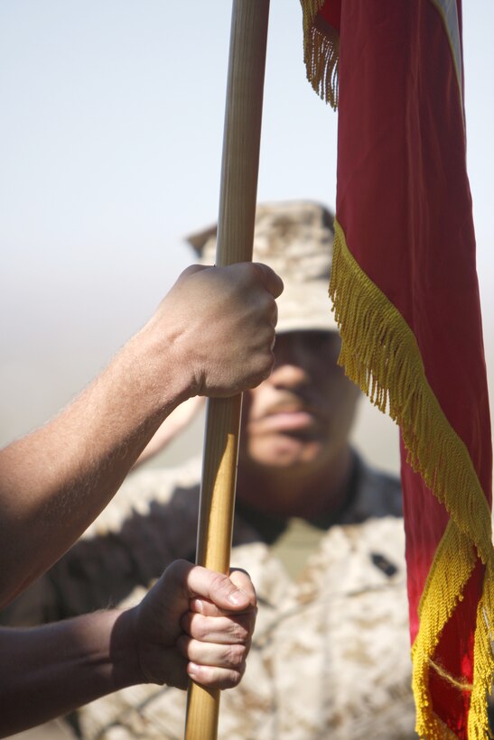 Lt. Col. Timothy G. Burton [holding flag], the incoming commander, grips the unit colors of Marine Unmanned Aerial Vehicle Squadron 3 during a change of command ceremony at the Combat Center's Lance Cpl. Torry L. Gray Field June 17. Sgt. Maj. Rufino Mendez Jr. [background], the unit's sergeant major, salutes as the new commanding officer takes charge of the unit.