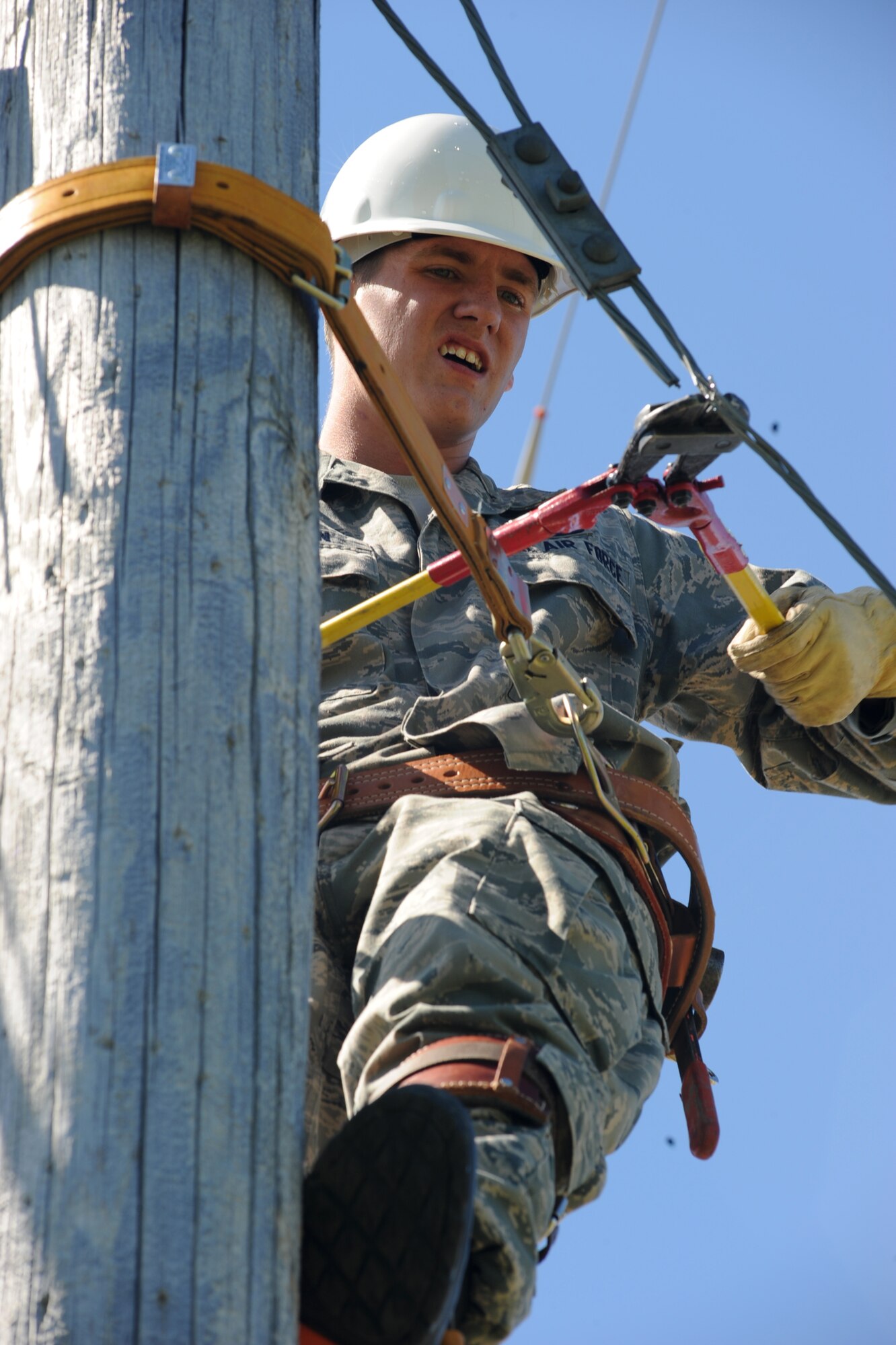 Airman 1st Class Patrick McFadden, an electrical systems apprentice with the 319th Civil Engineer Squadron, concentrates hard as he cuts an old telephone line that is no longer in use here June 16. The 319 CES is in the process of deconstructing the old telephone pole lines due to the fact base telephone lines are now buried. (U.S. Air Force photo by Airman 1st Class Amber Price)