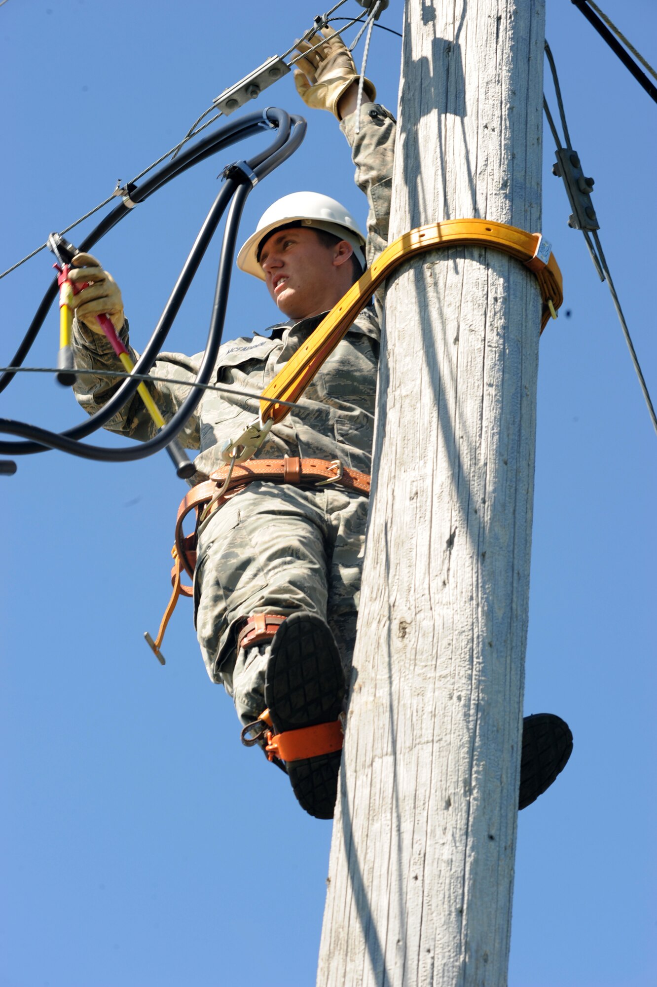 Airman 1st Class Patrick McFadden, an electrical systems apprentice with the 319th Civil Engineer Squadron, cuts an old telephone line here June 16. The 319 CES is in the process of deconstructing the old telephone pole lines due to the fact base telephone lines are now buried. (U.S. Air Force photo by Airman 1st Class Amber Price)