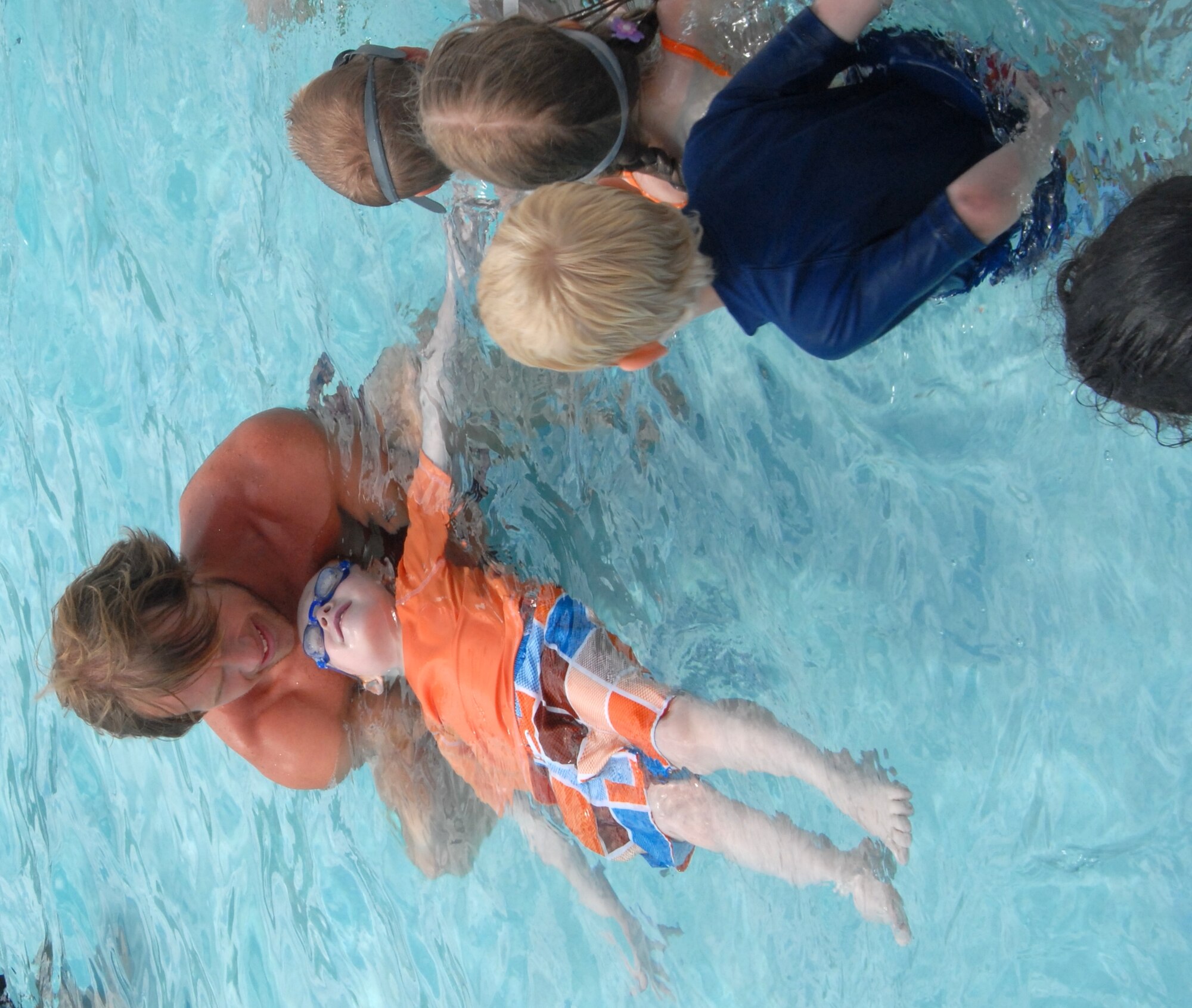Dason Tucker, a head lifeguard at China Beach pool, shows children how to float as part of the swimming class June 16. Mr. Tucker has been a lifeguard at Goodfellow for the last three years. Youth swimming lessons run until Aug.6. Call China Beach pool at 325-654-3226 to register. (U.S. Air Force photo/Connie Hempel)