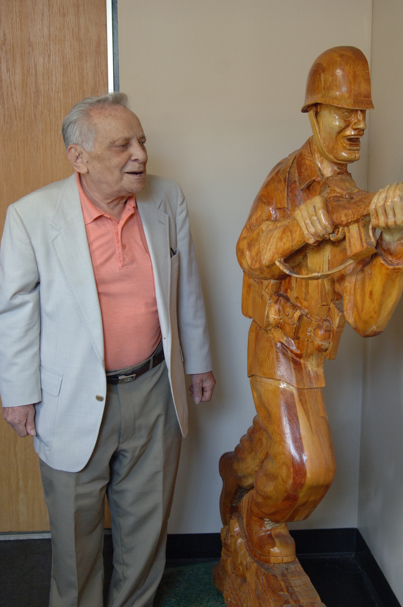 Camillo Signora reunites with the wooden replica of the Ultimate Weapon statue he created in 1984. He visited the statue, now displayed in the foyer of the Dix command conference room, during an Army birthday celebration Monday. (U.S. Army photo/ Jennifer McCarthy)