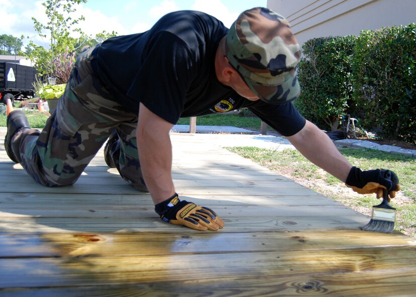 Air Force Reserve Tech. Sgt. Tony Nard, 919th Civil Engineer Squadron, paints on a waterproof sealant to protect a wooden deck project at Hurlburt Field, Fla. Members of the Duke Field, Fla., squadron built the deck June 3-4 for the Children’s Learning Center as part of the “Nature Explore Classroom.” (U.S. Air Force photo/Tech. Sgt. Cheryl Foster.)