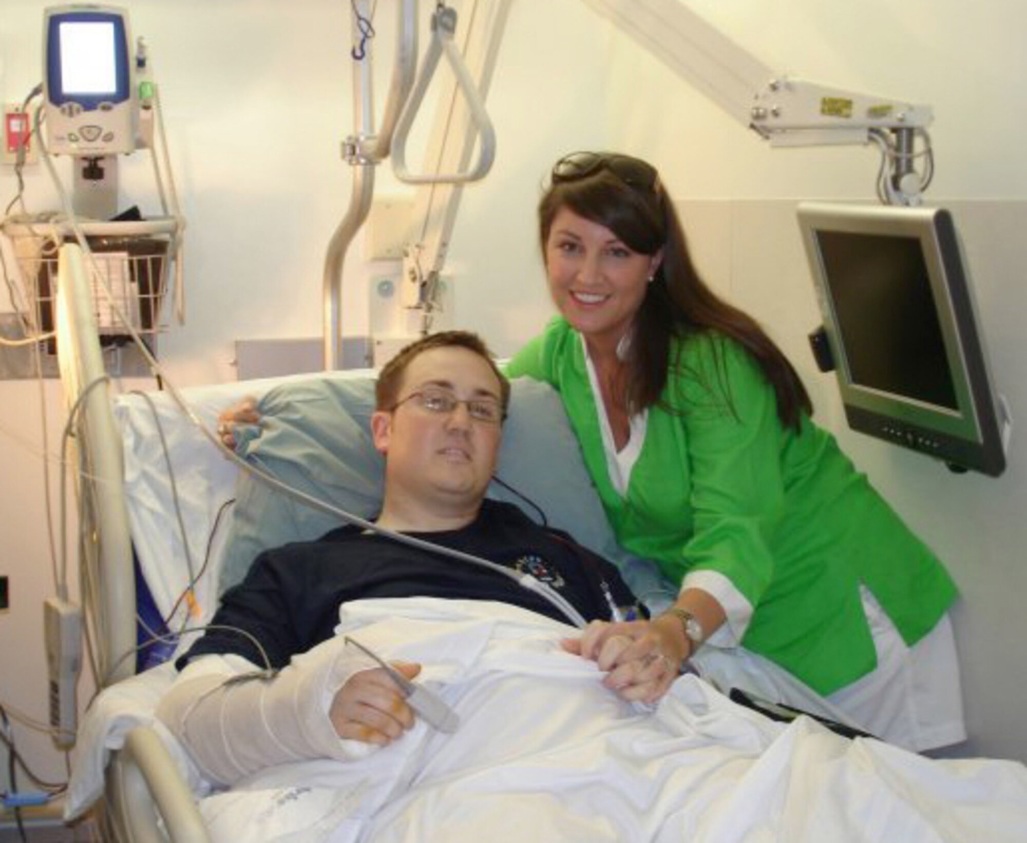 WASHINGTON, D.C. -- Staff Sgt. David Flowers, an Explosive Ordnance Disposal technician from Barksdale Air Force Base, La., poses with his wife Elizabeth from his hospital bed at Walter Reed Medical Center in Washington, D.C.  Sergeant Flowers lost his right leg below the knee, completely shattered his left leg and fractured his right arm and wrist when he stepped on an anti-personnel land mine in Afghanistan on May 11, 2009. (COURTESY PHOTO). 