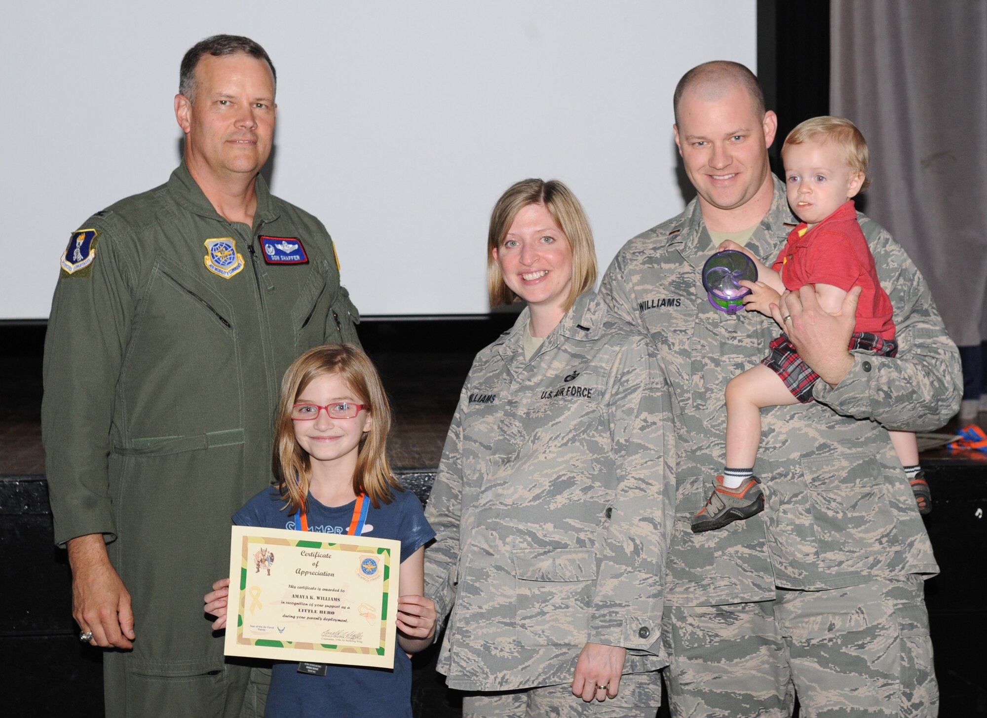 Col. Don Shaffer, 319th Air Refueling Wing commander, Amaya Williams, 1st Lt. Christine Williams, 319th Communications Squadron, 2nd Lt. James Williams, 319th Aircraft Maintenance Squadron and their son Kai (from left to right), pose for a picture after awarding Amaya, the Little Hero award during the Little Hero Ceremony, June 16 at the Community Activity Center. The Little Hero award recognizes the support and service of the children of active-duty parents, and the recipients were nominated by their parents for their contributions to their success in the military. (U.S. Air Force photo by Airman 1st Class Amber Price)