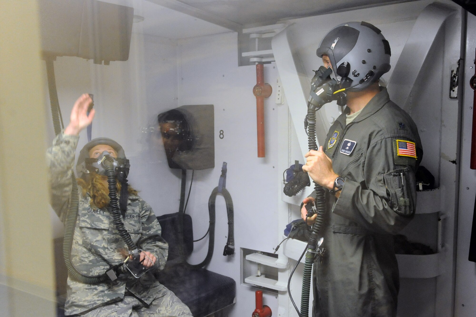 Lt. Col. Randy McCalip, 19th Medical Group, instructs 2nd Lt. Carmen Gulley, a 19th MDG student, how to deal with a rapid decompression situation by gang-loading her regulator June 11 during a chamber flight. Gang loading a regulator during a rapid decompression can provide emergency oxygen and prevent foreign particles entering the mask. (U.S. Air Force photo by Senior Airman Ethan Morgan)