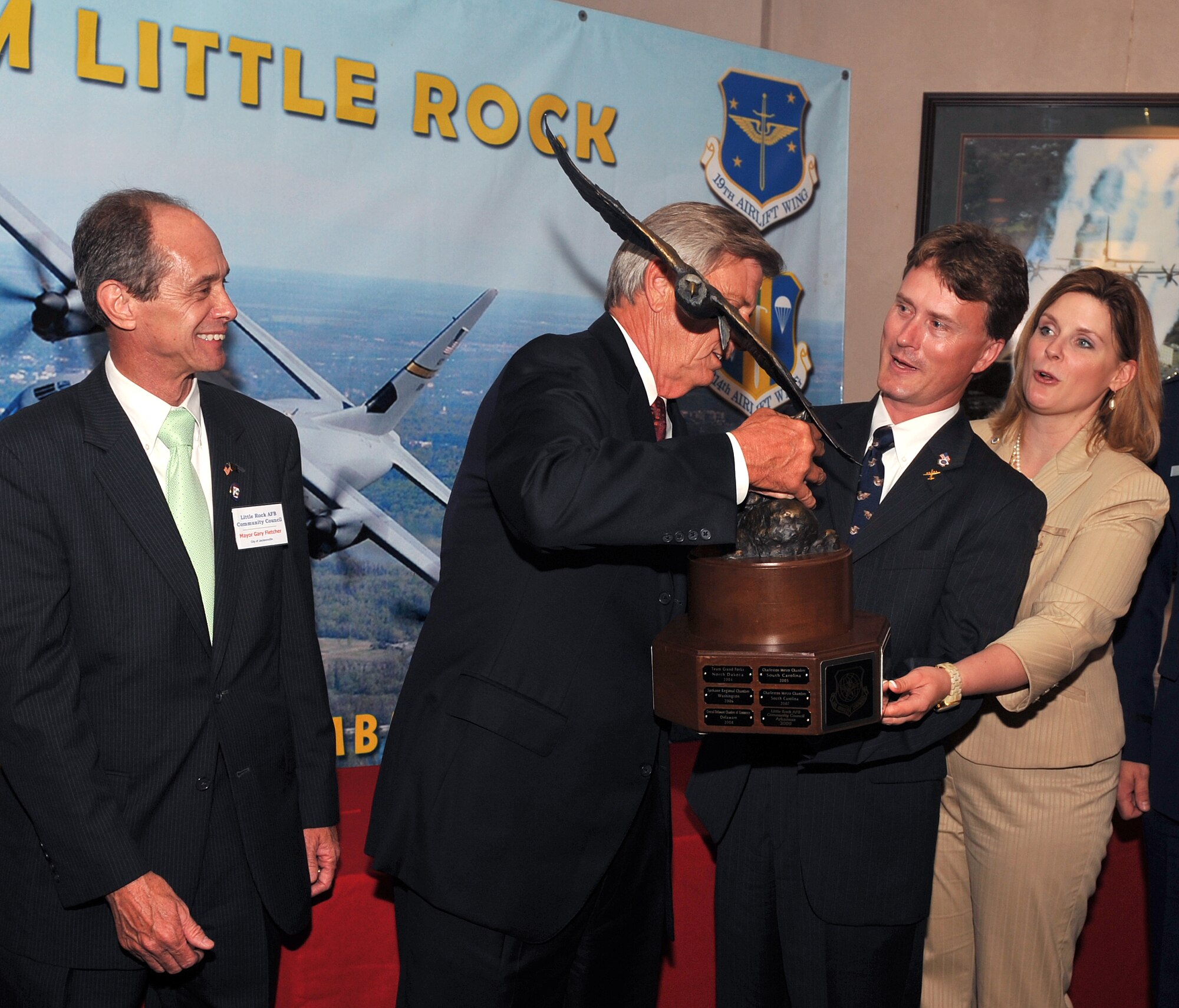 (From right to left) Kristina Jones and Gray Bridwell, Abilene Chamber of Commerce Military Affairs Committee members, present the Abilene Trophy to Arkansas Gov. Mike Beebe, who then handed it off to Jacksonville Mayor Gary Fletcher. Mayor Fletcher passed the trophy to other area city representatives to symbolically represent the continued support each of the areas' cities show to the members of Team Little Rock.