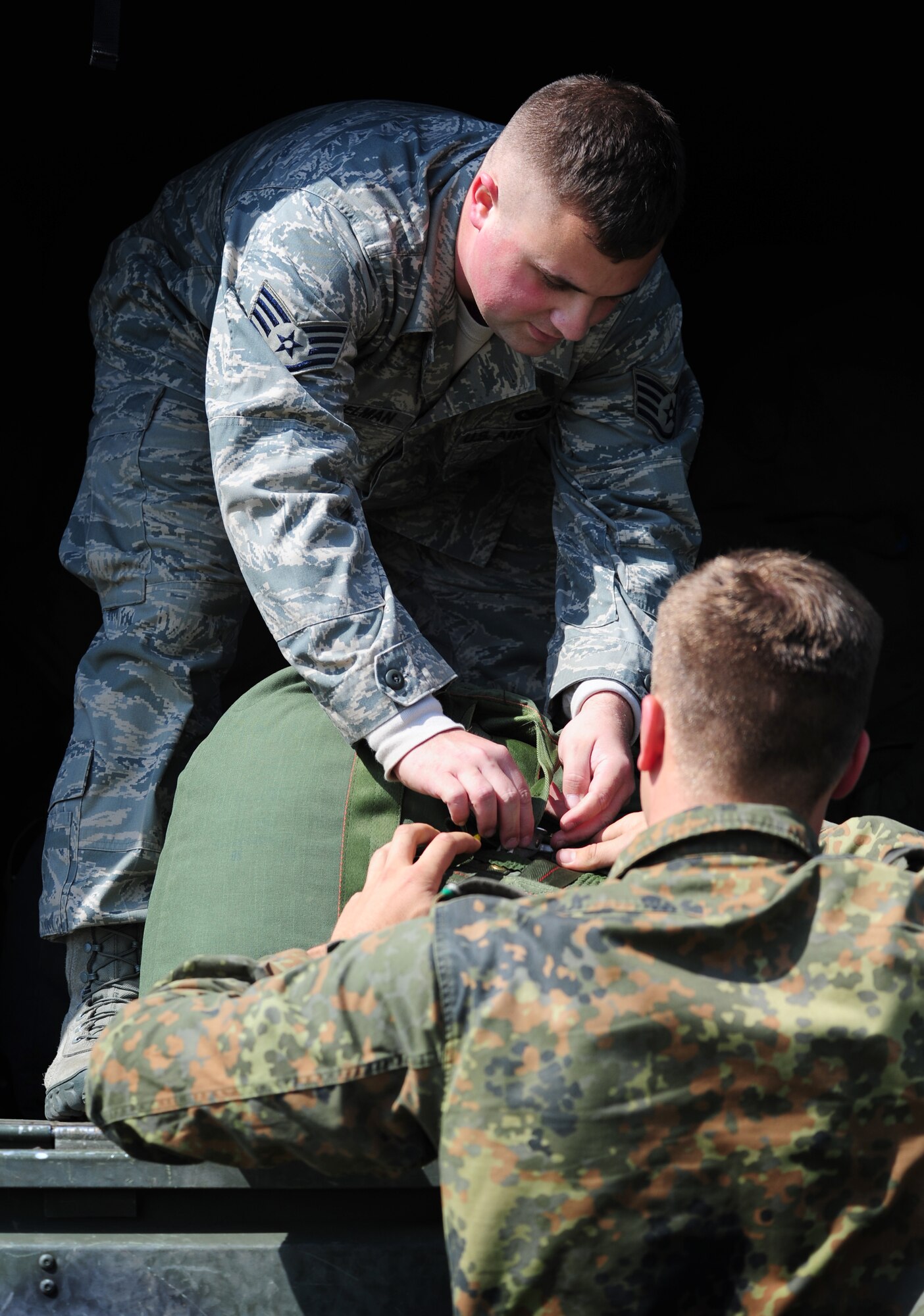 U.S. Air Force Staff Sgt. Joshua Wesselman, 435th Security Forces Squadron, recovers a personnel parachute from a German paratrooper just after he landed at the drop zone, Alzey, Germany, June 14, 2010. This airborne jump is part of what is officially known as NATO Jump Week and is the first time a NATO jump is conducted from a C-17. Five NATO countries participated in this annual event to support one of United States Air Forces in Europe's top priorities; building partnerships. (U.S. Air Force photo by Staff Sgt. Jocelyn Rich)