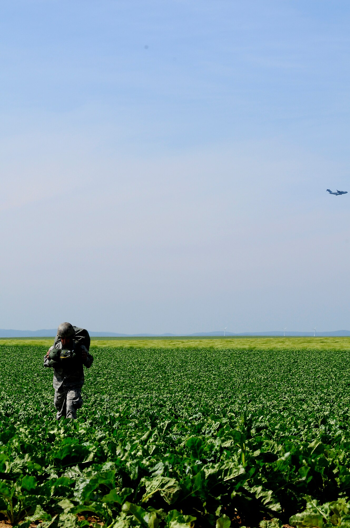 A U.S. Air Force Airman makes his way to a rally point after their jump as a C-17 Globemaster III flies over to drop the next stick of jumpers, Alzey, Germany, June 16, 2010. This airborne jump is officially known as NATO Jump Week and is the first time a NATO jump is conducted from a C-17. Five NATO countries participated in the annual event to support one of United States Air Forces in Europe's top priorities; building partnerships. (U.S. Air Force photo by Airman 1st Class Brea Miller)