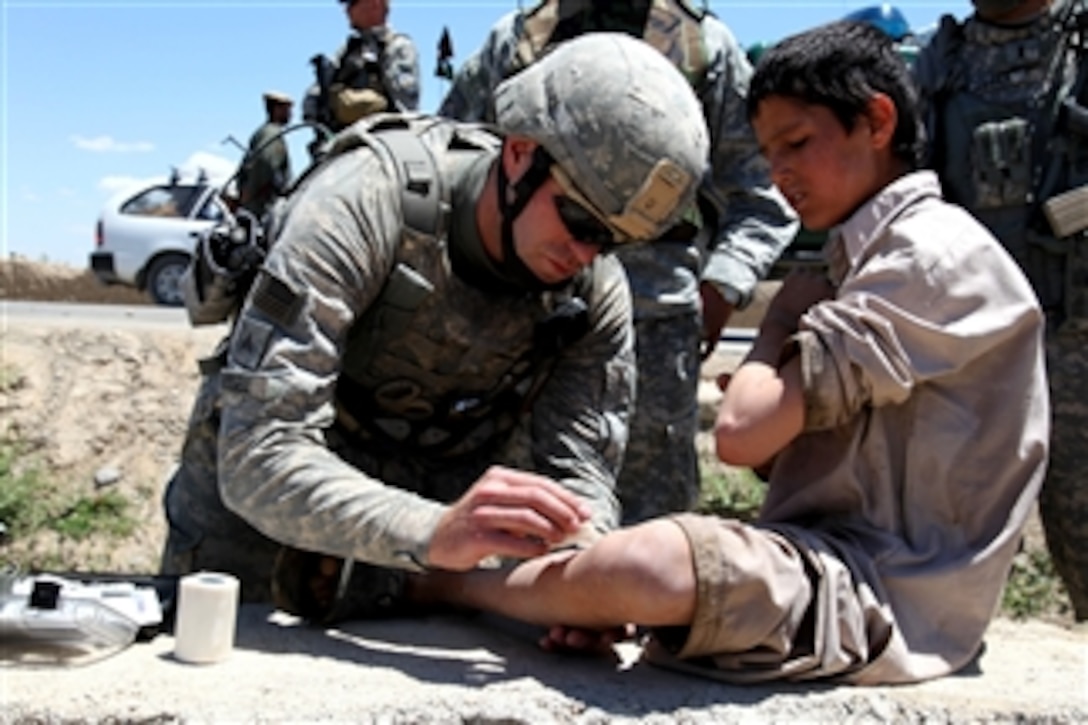 U.S. Army Sgt. John Russell (left) assigned to the 173rd Airborne Brigade Combat Team gives a small child medical care in the Logar province of Afghanistan on June 9, 2010.  