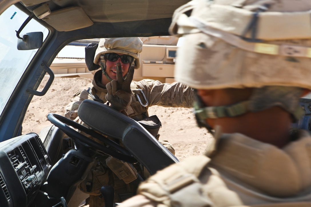 Lance Cpl. Mathew Humbert, with Marine Wing Support Squadron 274, flashes a quick peace sign while searching a gravel truck here June 17. Humbert helped search more than 100 trucks throughout the day.