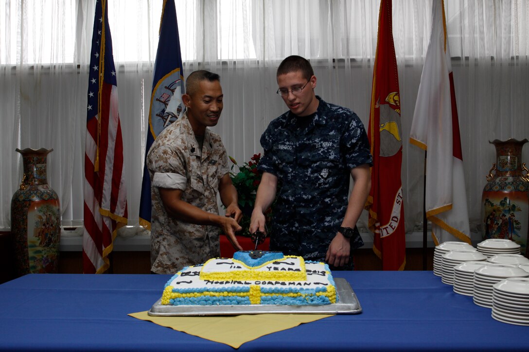 Chief Simeon Cadavos, the oldest corpsman on the air station, and Seaman Apprentice Zachary Hallowood, the youngest corpsman on the air station, cut a cake in celebration of the 112th birthday of the Hospital Corpsmen at the south side mess hall here June 17. During the Spanish-merican War, Congress approved a bill which created the naval rates of hospital apprentice, hospital apprentice first class and hospital steward on June 17, 1898, officially bringing the hospital corpsmen to birth.