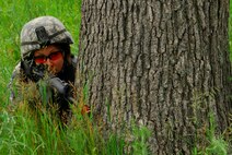 Staff Sgt. Leigh Downing, 115th Security Forces Squadron, takes cover behind a tree while on a simulated combat patrol at Volk Field Combat Readiness Training Center, Wis., June 14, 2010. Downing was providing cover for fellow Security Forces members inside a village. (U.S. Air Force Photo by Staff Sgt. Stephen Montgomery)