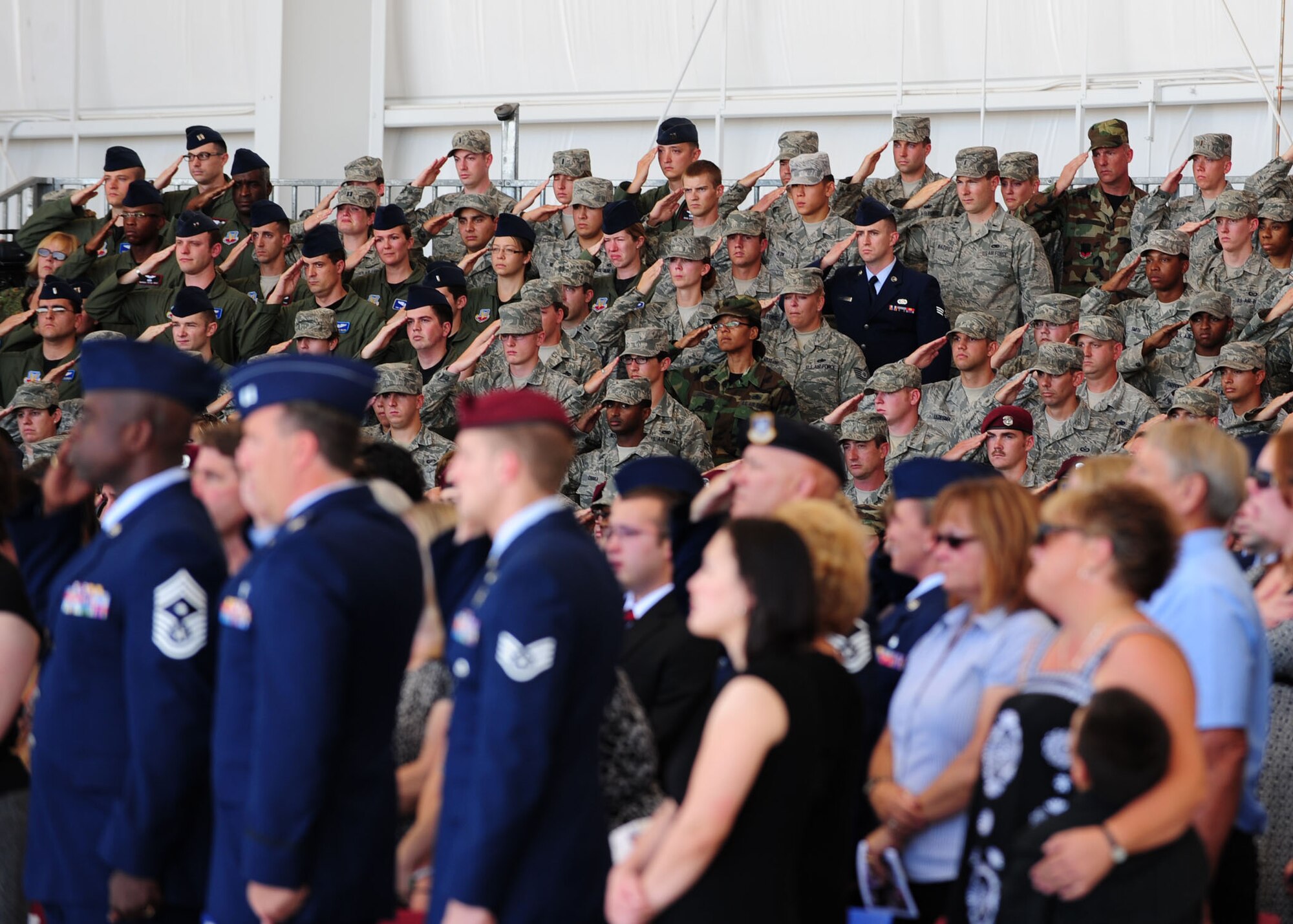 Airmen and family members pay their respects while Taps is played during the memorial service for Tech. Sgt. Michael Flores and Senior Airman Benjamin White here June 17. More than 1,200 guests attended the memorial service for the two pararescuemen who were killed June 9 in southeastern Afghanistan while on a deployment in support of Operation Enduring Freedom.  (U.S. Air Force photo/Airman 1st Class Jerilyn Quintanilla)