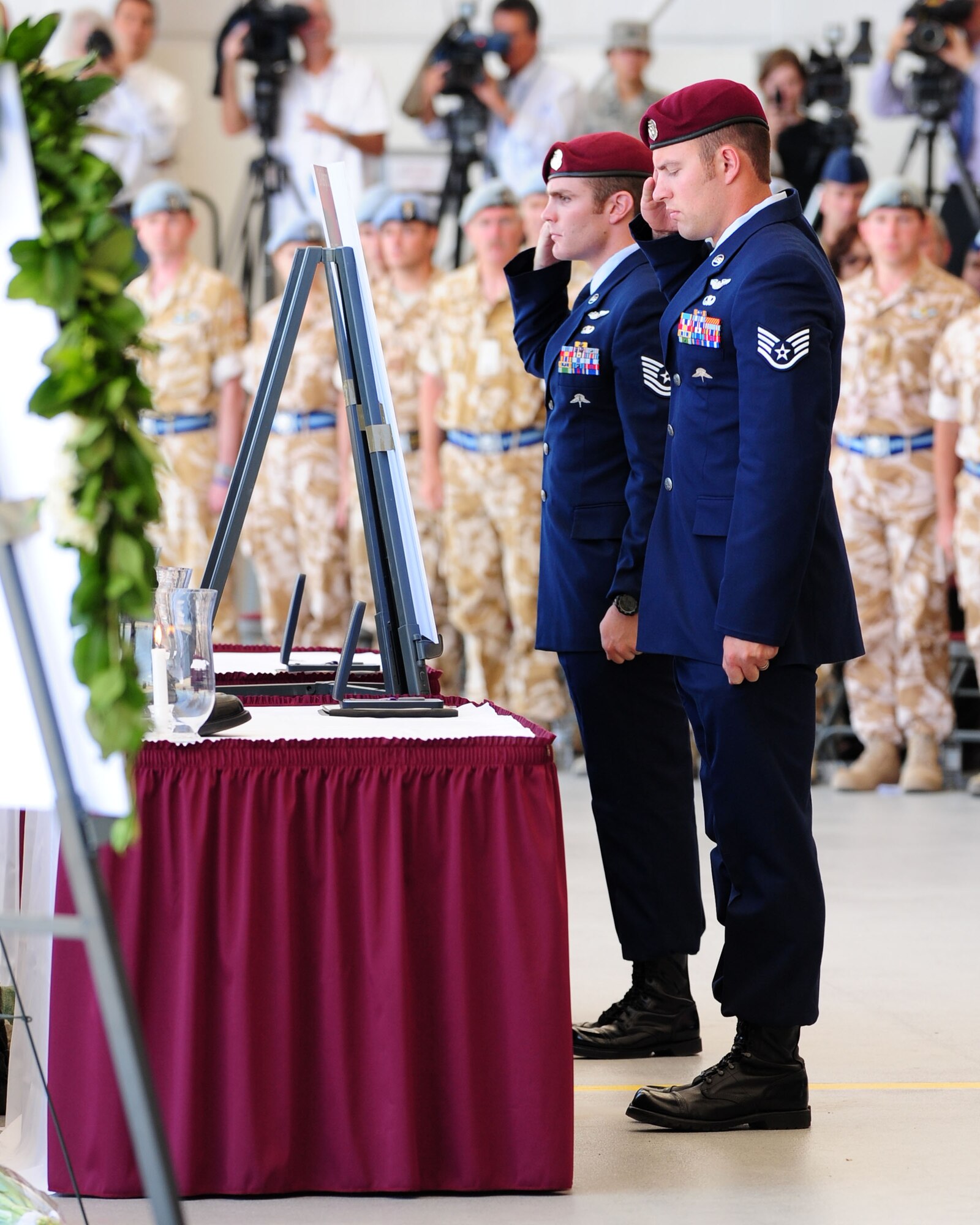 Two Airmen from the 48th Rescue Squadron render salutes during a memorial service in honor of Tech. Sgt. Michael Flores and Senior Airman Benjamin White here June 17. More than 1,200 guests attended the memorial service for the two pararescuemen who were killed June 9 in southeastern Afghanistan while on a deployment in support of Operation Enduring Freedom. (U.S. Air Force photo/Airman 1st Class Jerilyn Quintanilla)