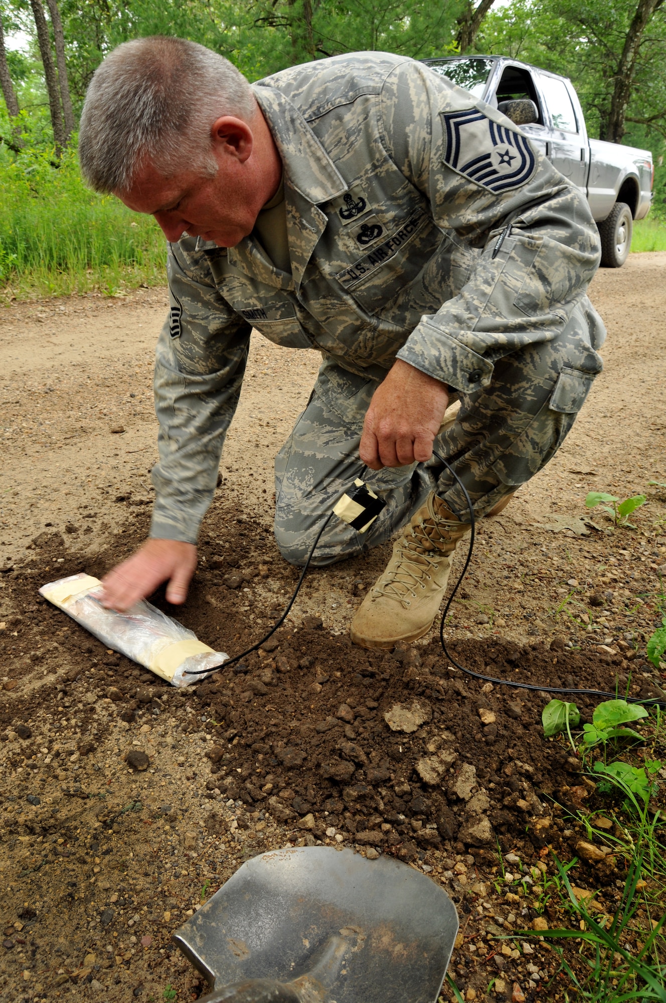 Senior Master Sgt. Ed Smith, 115th Fighter Wing Explosive Ordinance Disposal Flight, lays a simulated pressure plate detonation device in the road during convoy training at Volk Field CRTC, Wis., June 12, 2010.  Sgt. Smith assisted in leading the 115FW Civil Engineering Squadron during annual training.(U.S. Air Force photo by Staff Sgt. Christen Bloomfield)