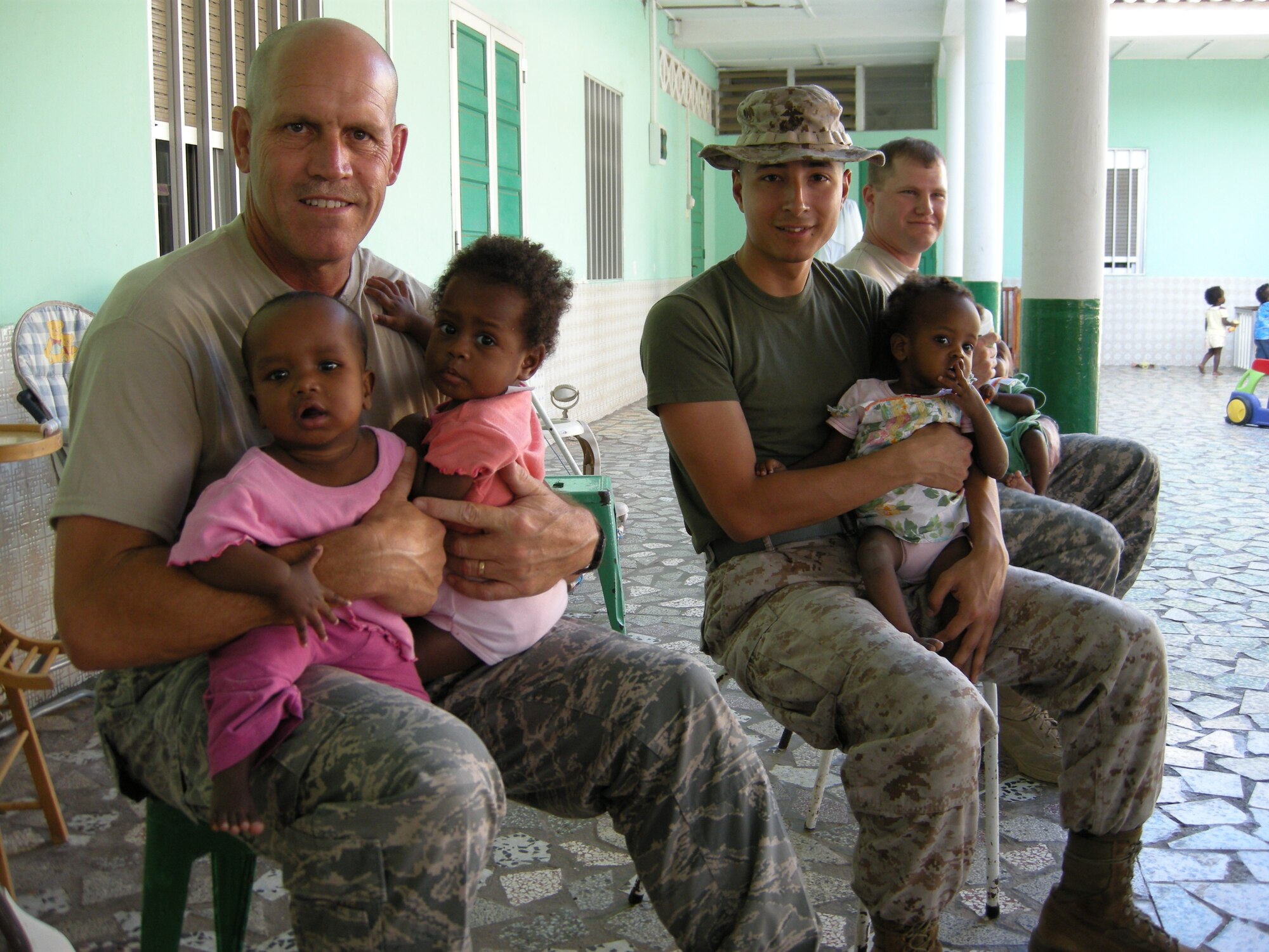 161st ARW MSgt David Zibell (left) and other team members holding babies at the Djibouti orphanage, part of the efforts that resulted in Zibell receiving the Military Outstanding Volunteer Service Medal.