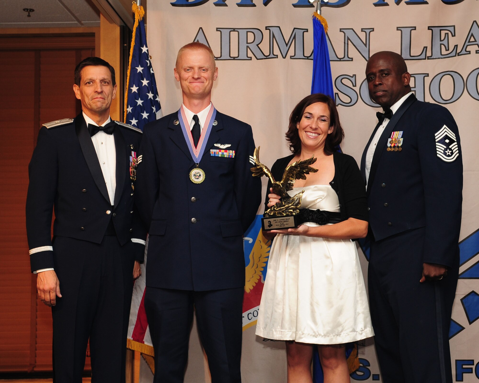 Senior Airman Steven Geisbert (center), from the 42nd Electronic Combat Squadron, poses with Brig. Gen. Paul Johnson (left), 355th Fighter Wing commander, Chief Master Sgt. Vincent Howard, 355th Fighter Wing acting command chief, and Ellen Jimenez, president of the Military Affairs Committee, after being presented with the John L. Levitow Award at the Airmen Leadership School graduation ceremony for Class 10-F at the Mirage Club here June 17. Forty-six enlisted members graduated from Davis-Monthan's Airmen Leadership School, which prepares senior airmen for supervisory duties and fosters a commitment to the profession of arms. The Levitow award is the highest honor awarded during enlisted professional military education to the student who is most outstanding in performance evaluations, demonstrated leadership, and teamwork. (U.S. Air Force photo/Airman 1st Class Jerilyn Quintanilla)