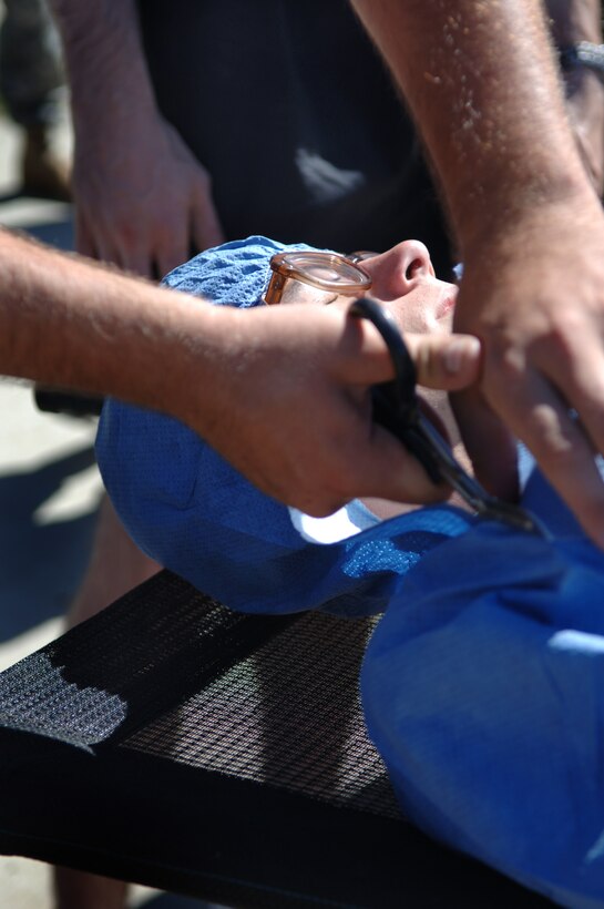 ELLSWORTH AIR FORCE BASE, S.D. -- Private 1st Class Kyle Spree, Army National Guard, 704th Chemical Company chemical, biological, radiological and nuclear specialist, cuts a protective suit off of a simulated casualties during the 2010 Golden Coyote exercise at Camp Lancer, Ellsworth Air Force Base, S.D., June 18.  The protective suit is worn to guard against possible CBRNE threats. (U.S. Air Force photo/Airman 1st Class Jarad Denton)