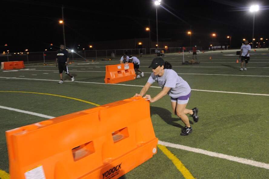 DYESS AIR FORCE BASE, Texas—Nikki Hill pushes a road block 15 yards across the football field June 18  as part of an obstacle course challenge sponsored by the Dyess Fitness Center here. Fit camp members and other Airmen participated on the course, which consisted of challenges such as push-ups, low crawls and tire flipping. (U.S Air Force photo/ Airman 1st Class Shannon Hall)