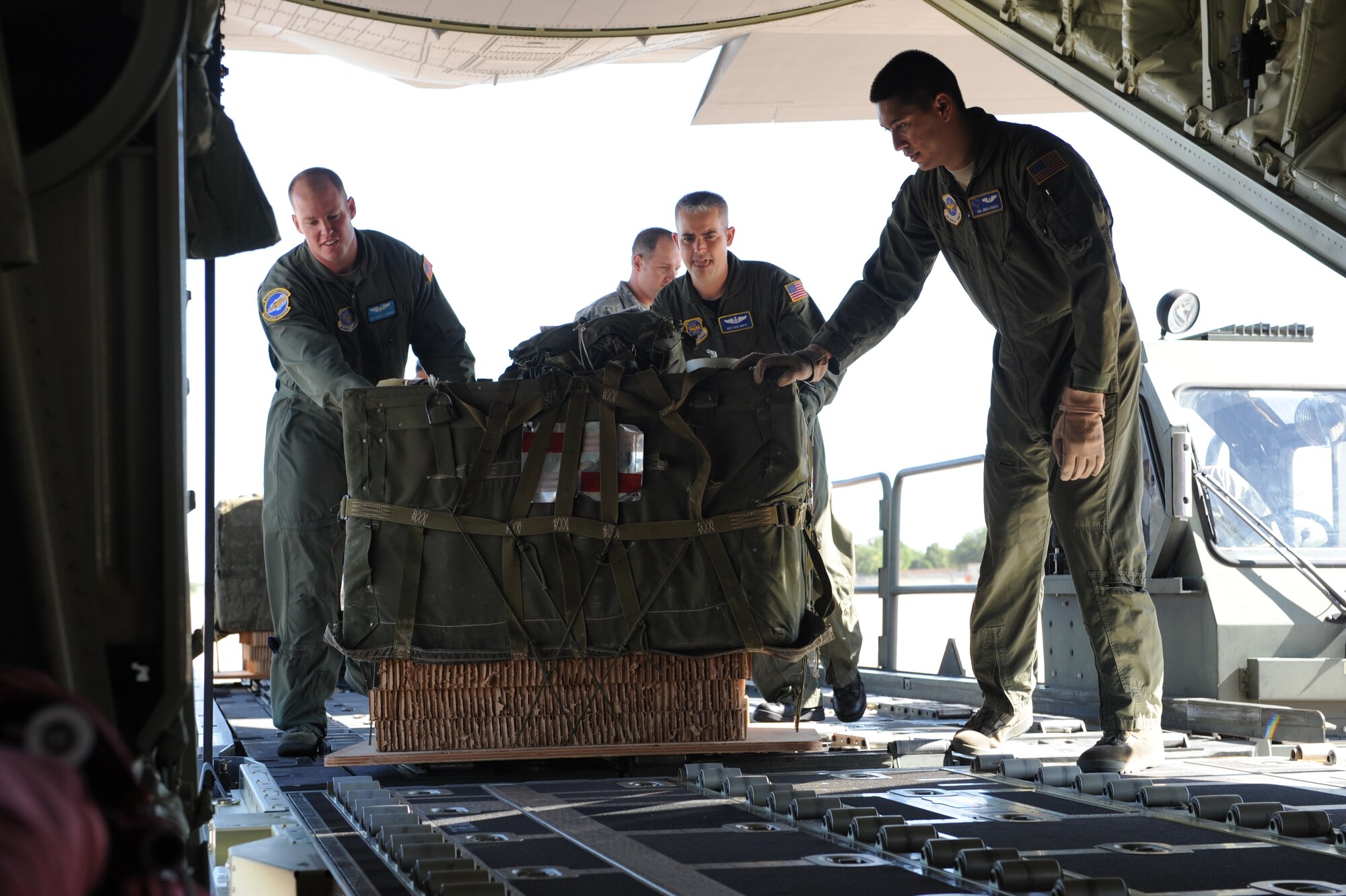 DYESS AIR FORCE BASE, Texas—(left to right) Tech Sgt. Charles Skidmore, Master Sgt. Steve Martin and Senior Airman Jason Ignacio, all from the 40th Airlift Squadron, load a bundle onto the C-130J Super Hercules June 17 as part of a 22-bundle mass container delivery system airdrop at Bronte Drop Zone over Bronte city to demonstrate the capabilities of the C-130J-model. The regular C-130 Hercules’ are only capable of carrying 16 bundles. The 317th Airlfit Group will be training more on this to help prepare them for deployments. In the course of two years all of the old C-130 Hercules’ will be replaced by the new J-model. (U.S Air Force photo/ Airman 1st Class Shannon Hall)