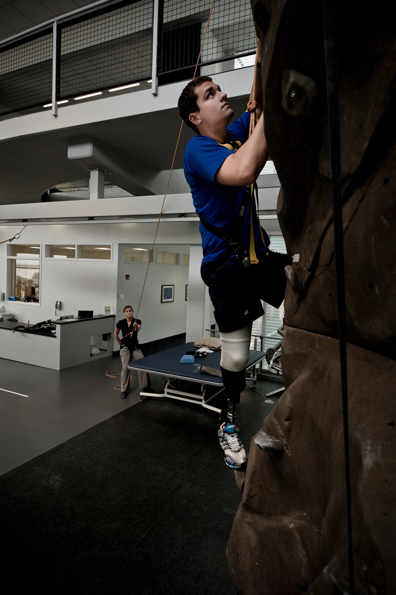 Conquering the rock climbing wall at the Center for the Intrepid is just one of the exercises physical therapist Alicia White (holding the safety rope) has McGuire perform. The rehabilitation therapy helps the lieutenant get used to the prosthetic he received after having his lower right leg amputated following a boating mishap last summer.
(TSgt Samuel Bendet)