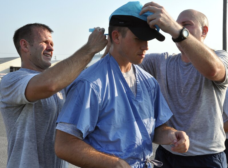 An Airman gets suited up in personal protective gear during a pit stop at Station 4 testing Self-Aid Buddy Care during the 96th Air Base Wing Fitness Event June 18. Hosted by the 96th Medical Group, the fitness event touted a medical theme. The 3-mile run was broken up with four stations with regular fitness exercises and also challenge exercises such as litter crawls, Self-Aid Buddy Care, a bedpan fill and a race to don PPE. (U.S. Air Force photo/Staff Sgt. Stacia Zachary)