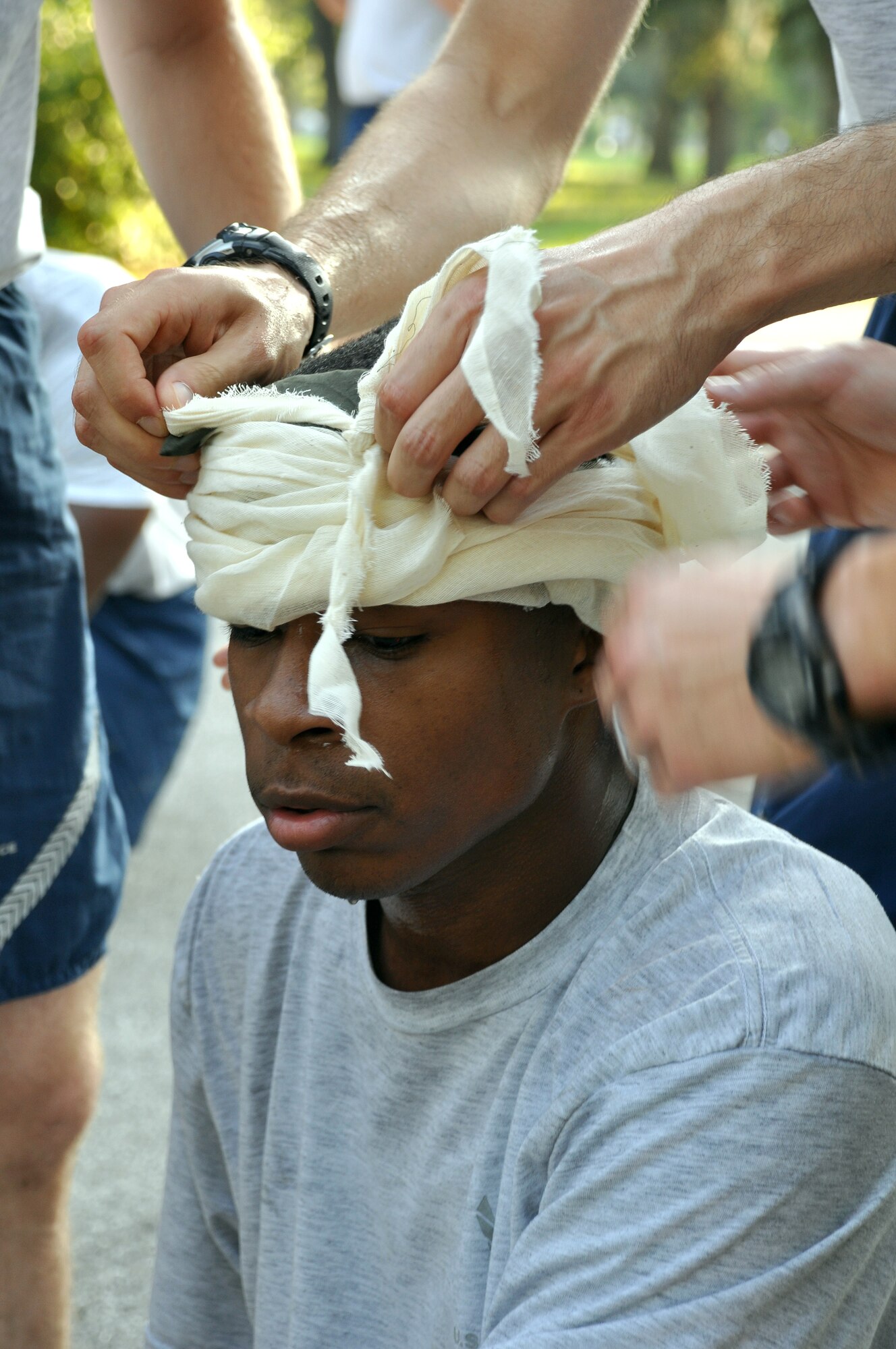 An Airman gets bandaged during a pit stop at Station 2 testing Self-Aid Buddy Care during the 96th Air Base Wing Fitness Event June 18. Hosted by the 96th Medical Group, the fitness event touted a medical theme. The 3-mile run was broken up with four stations with regular fitness exercises and also challenge exercises such as litter crawls, Self-Aid Buddy Care, a bedpan fill and a race to don personal protective equipment. (U.S. Air Force photo/Staff Sgt. Stacia Zachary)