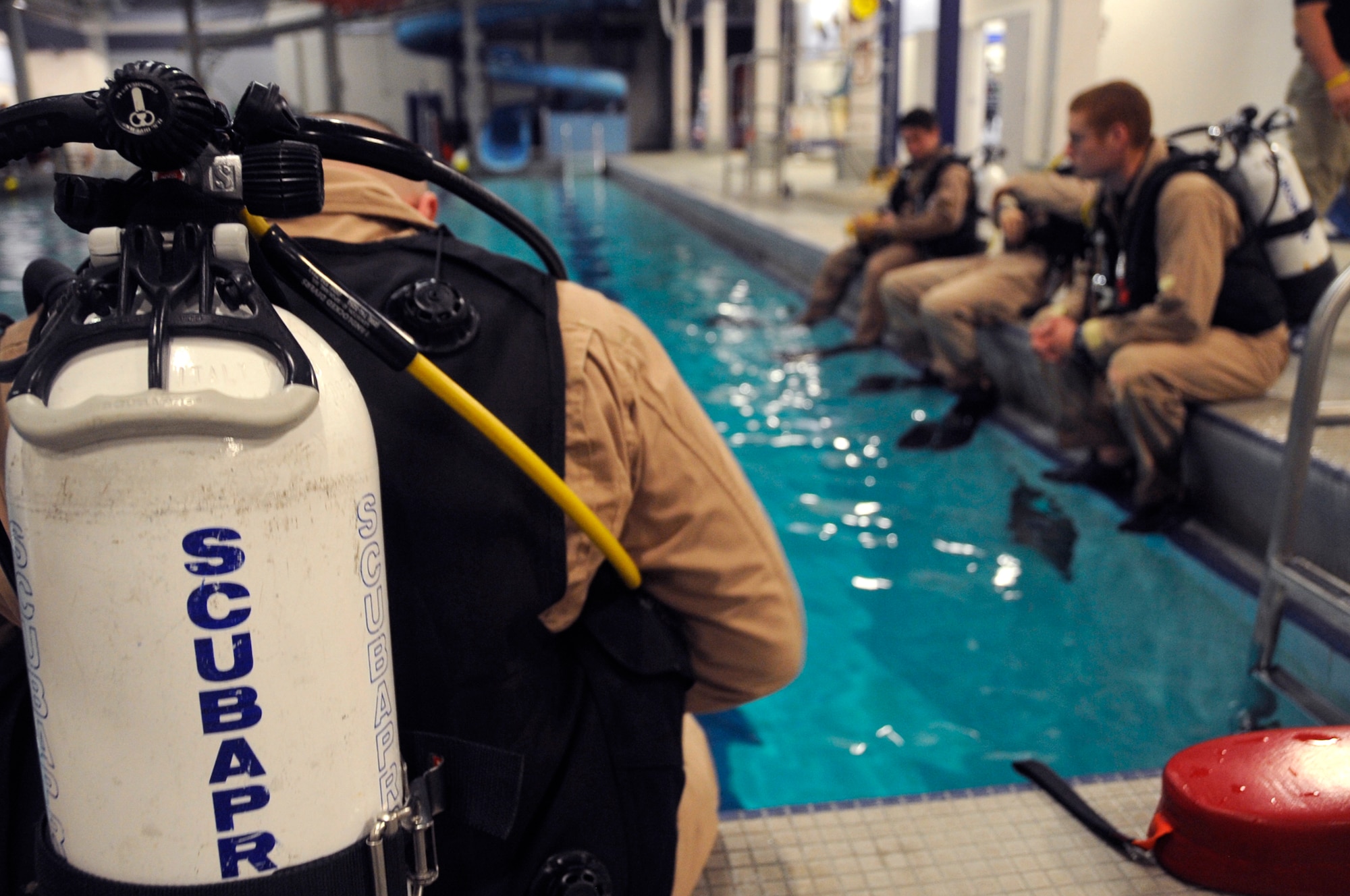 Instructors wait at the edge of the pool for an underwater survival training simulation to begin. The 10 instructors of the 22nd Training Squadron are also qualified on diving equipment. (U.S. Air Force photo/Staff Sgt. Chad Watkins)

