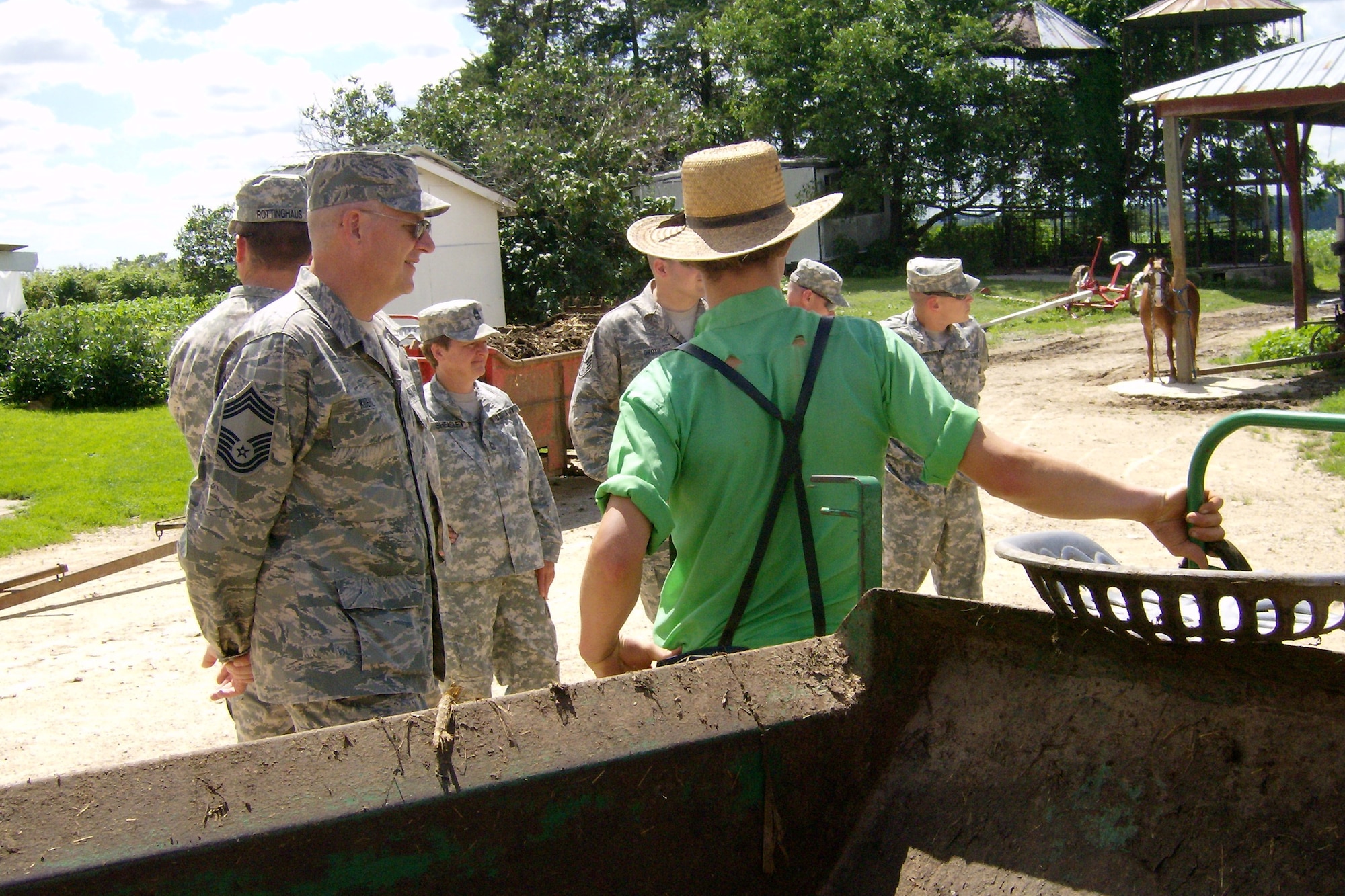 An Amish boy on his family's farm in northeast Iowa teaches Chief Master Sgt. Don Kuehl, left, and other members of the Iowa National Guard's 734th Agri-Business Development Team the finer points of using a manure spreader hauled by draft horses.