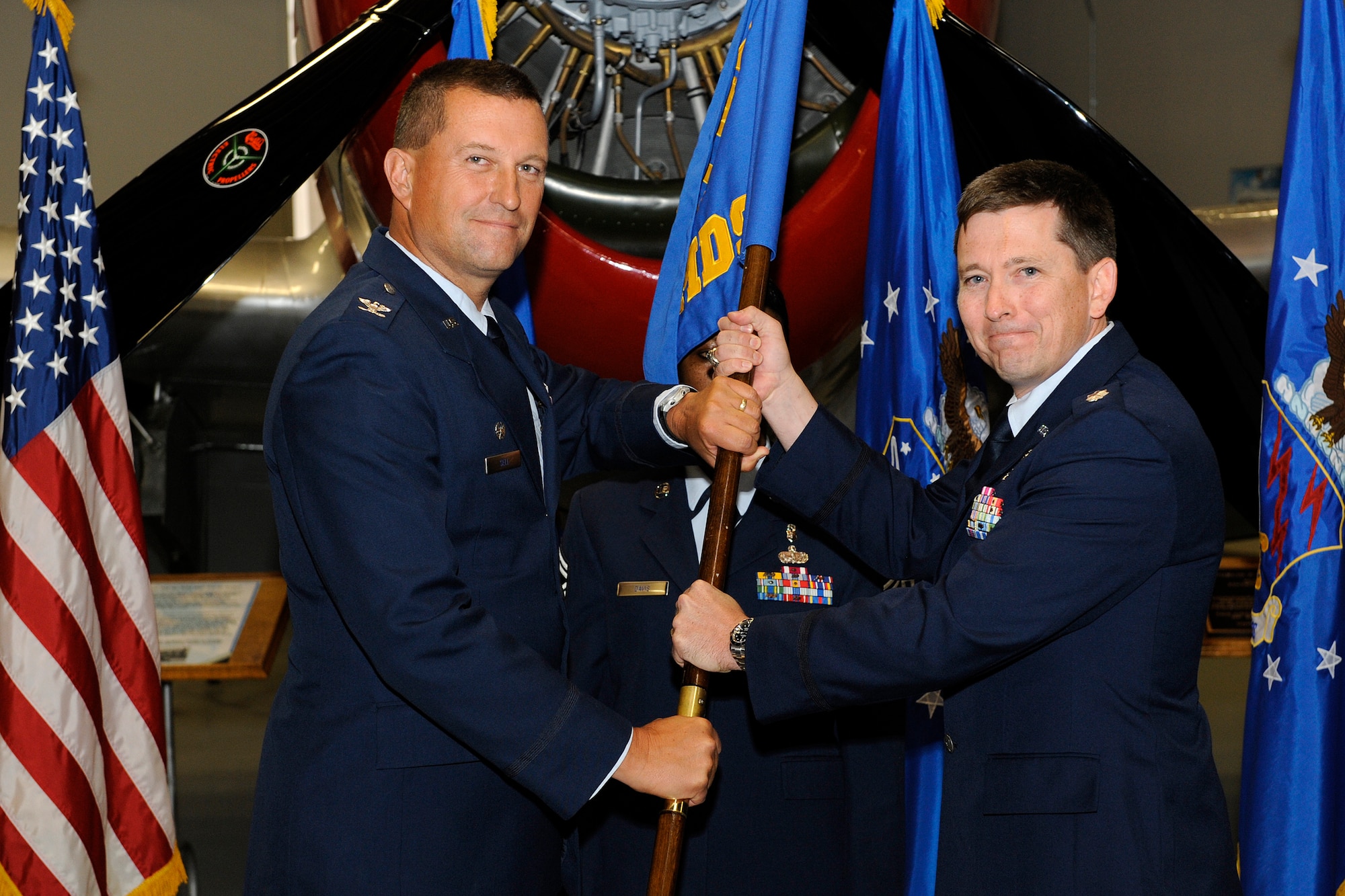 PETERSON AIR FORCE BASE, Colo. -- Col. John Sell (left), 21st Medical Group commander, passes the 21st Aerospace Medicine Squadron guidon to Lt. Col. Andrew Moore during a June 14 change of command ceremony at The Club. Colonel Moore assumed command of the 21st AMDS and will oversee flight medicine, public health, optometry, the health and wellness center, drug demand reduction, bioenvironmental engineering and aerospace and operational physiology. Lt. Col. Lori Lee, who relinquished command to Colonel Moore, took command of the 21st Medical Operations Squadron. (U.S. Air Force photo/Craig Denton)