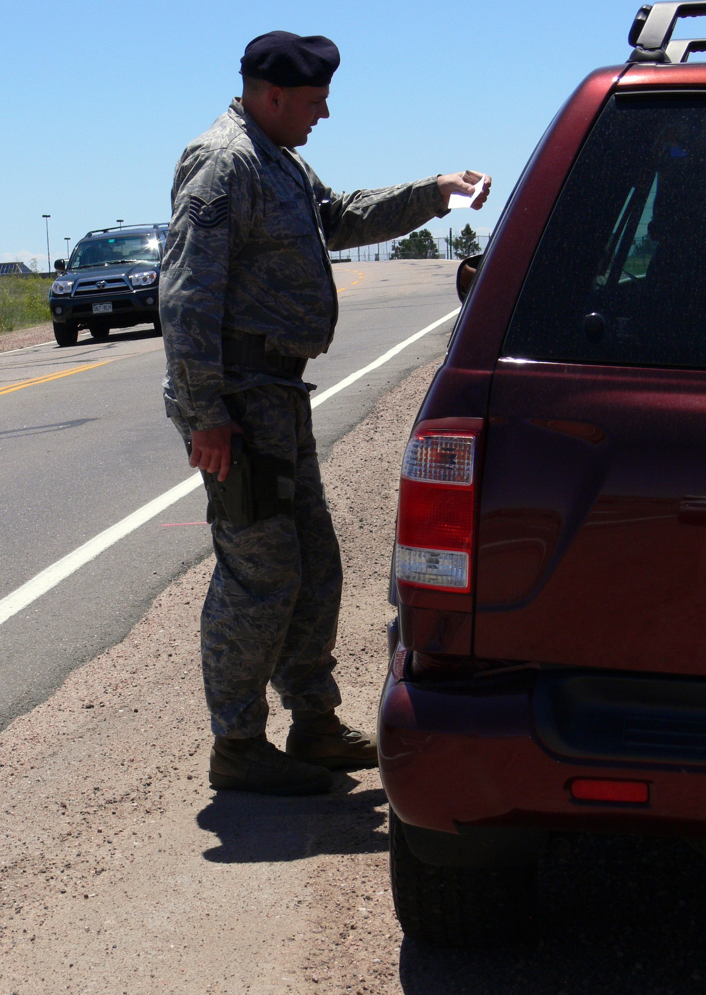 Tech. Sgt. Jeremy Babcock, 21st Security Forces Squadron, looks at the ID of a driver he stopped for speeding on Stewart Avenue June 15. The 21st SFS has stepped up traffic control as part of its integrated defense plan, which calls for higher visibility on and around the base. (U.S. Air Force photo/Monica Mendoza)